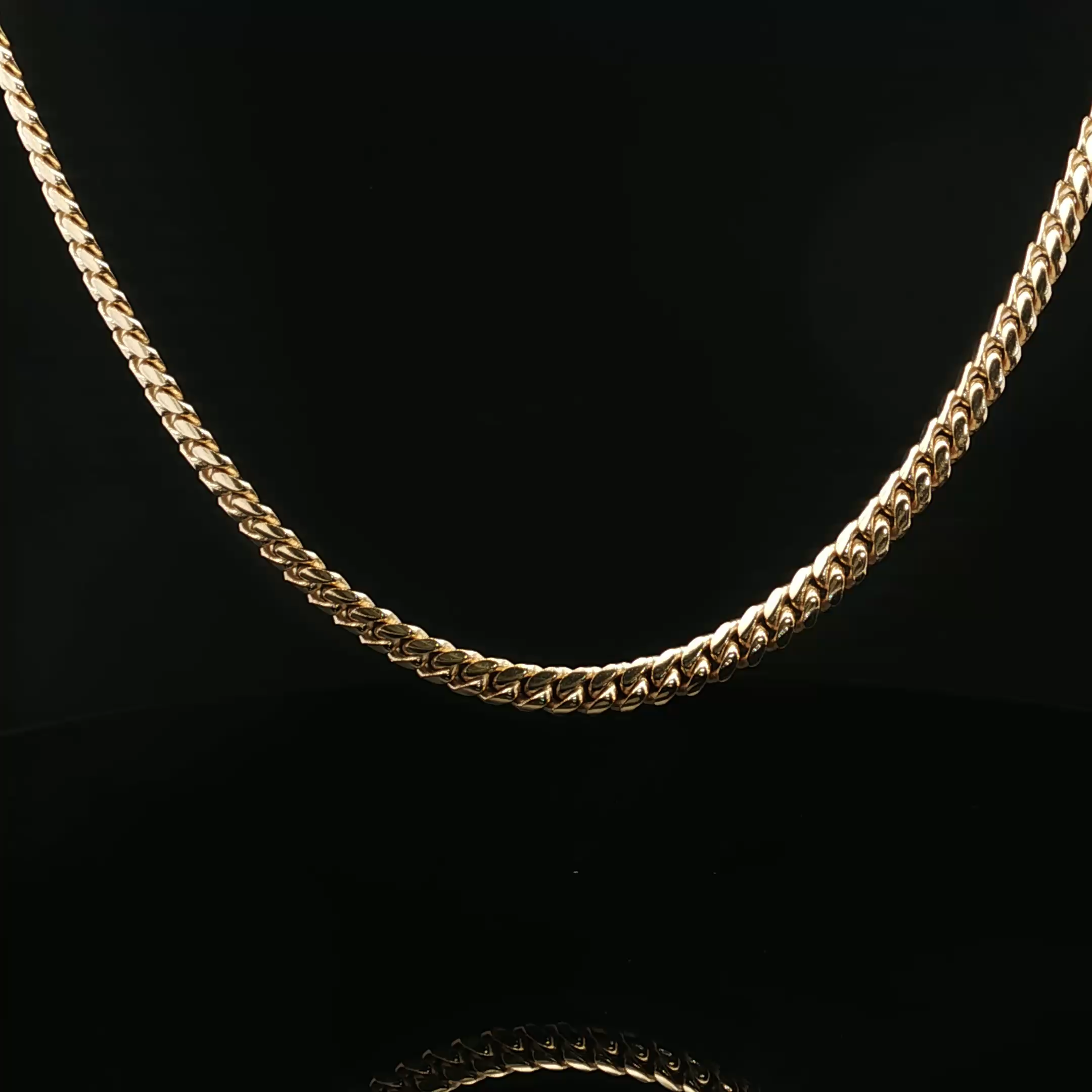 Close-up of a gold chain necklace with a black background.