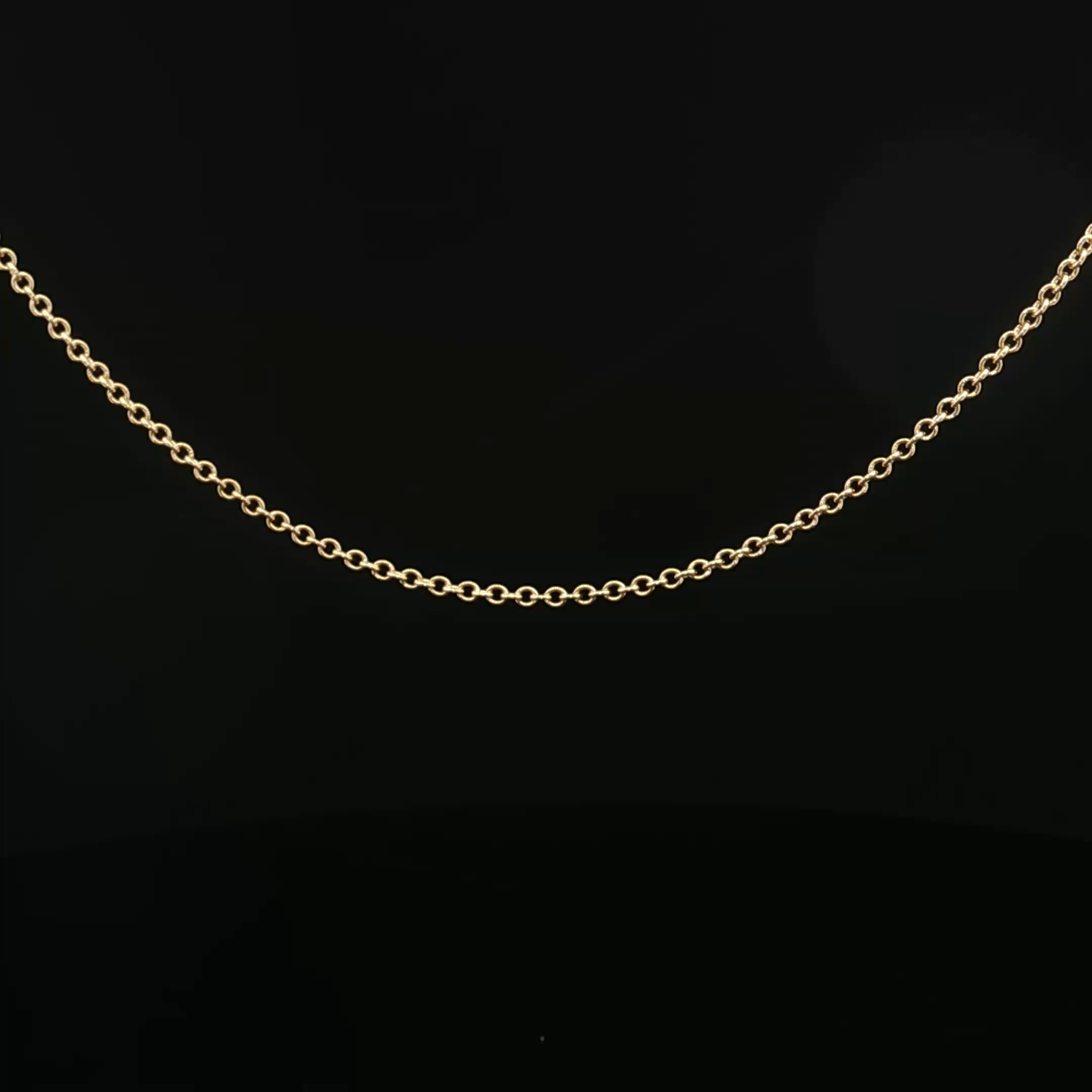 Close-up of a gold chain necklace against a black background.