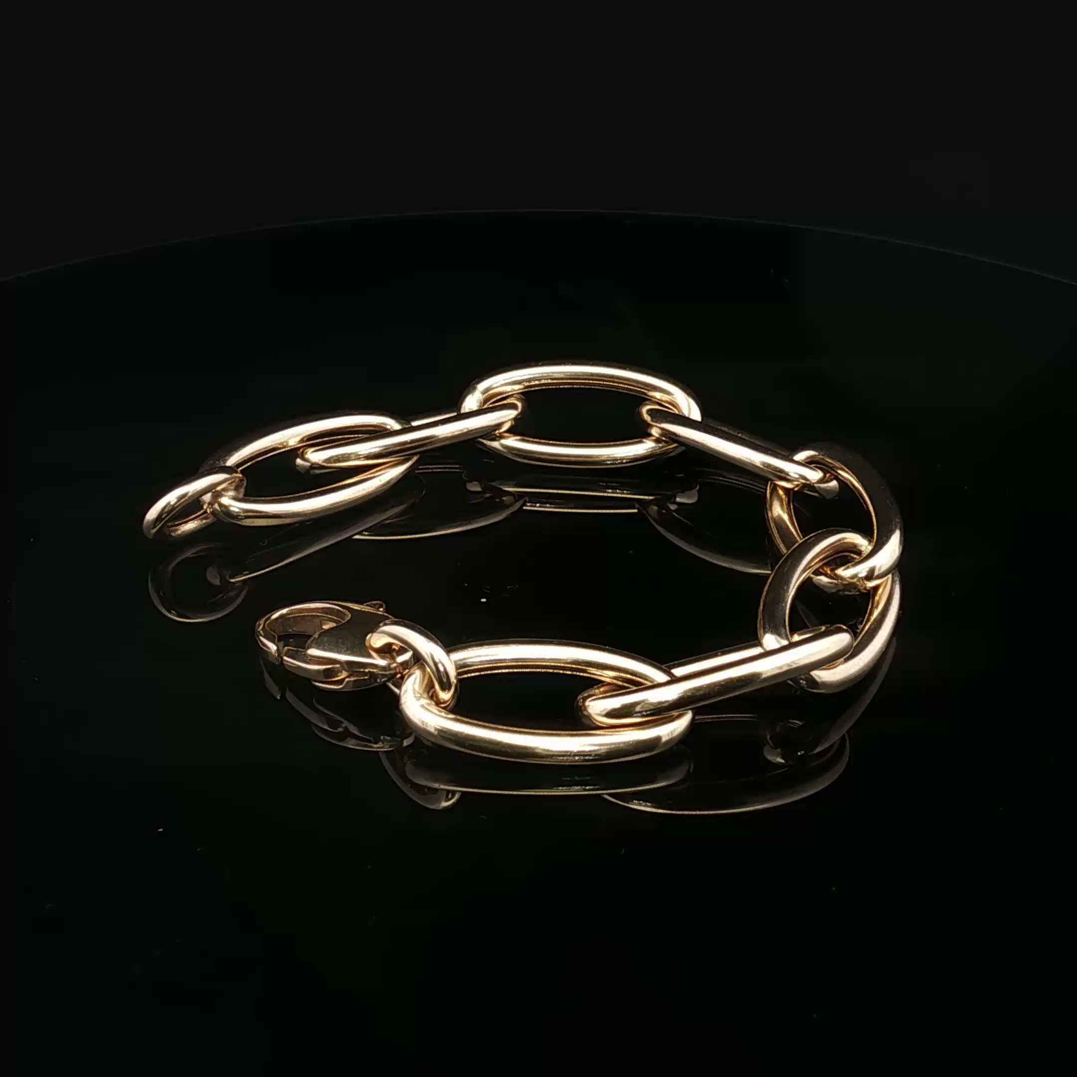 Close-up of gold-colored chain link bracelet against a black background.