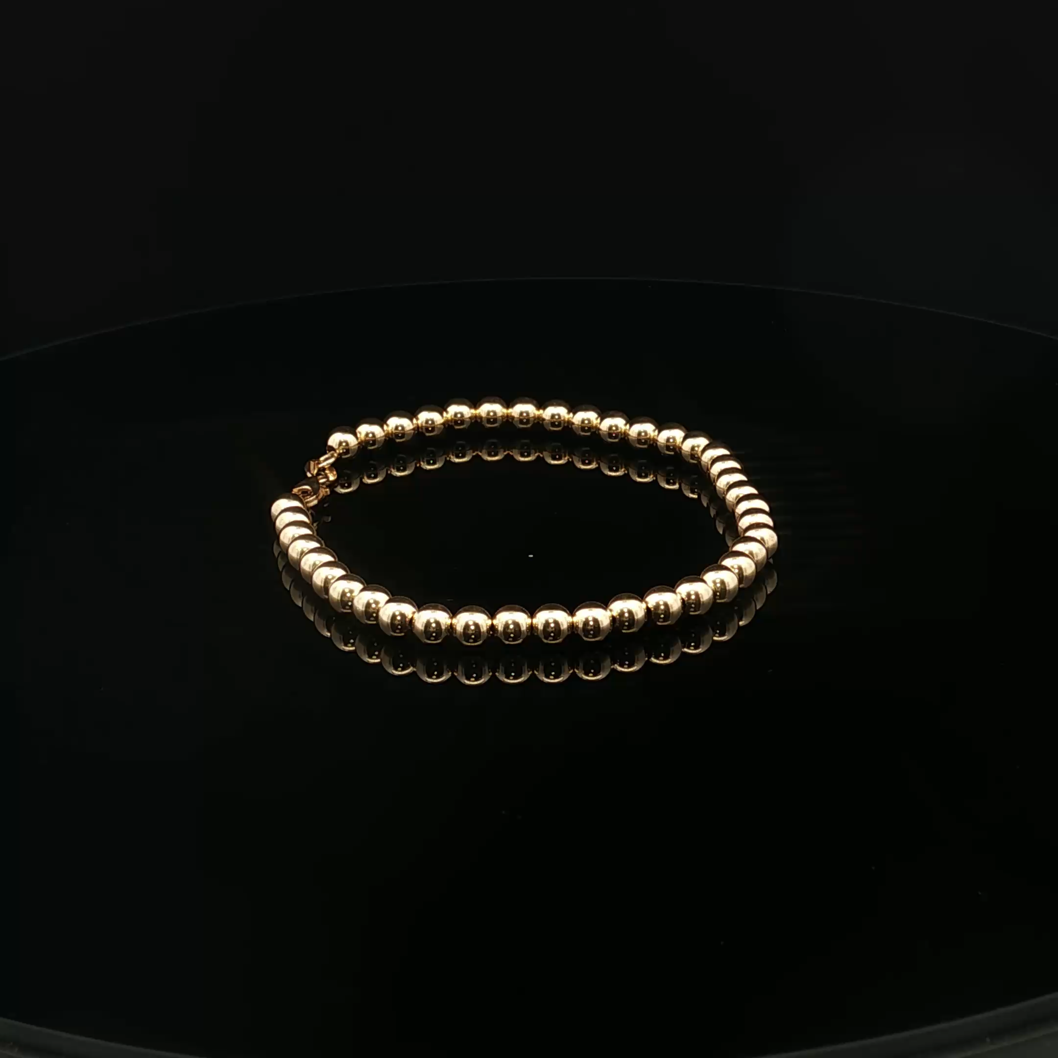 A string of pearl-like golden beads arranged in a circular shape illuminated against a dark background.
