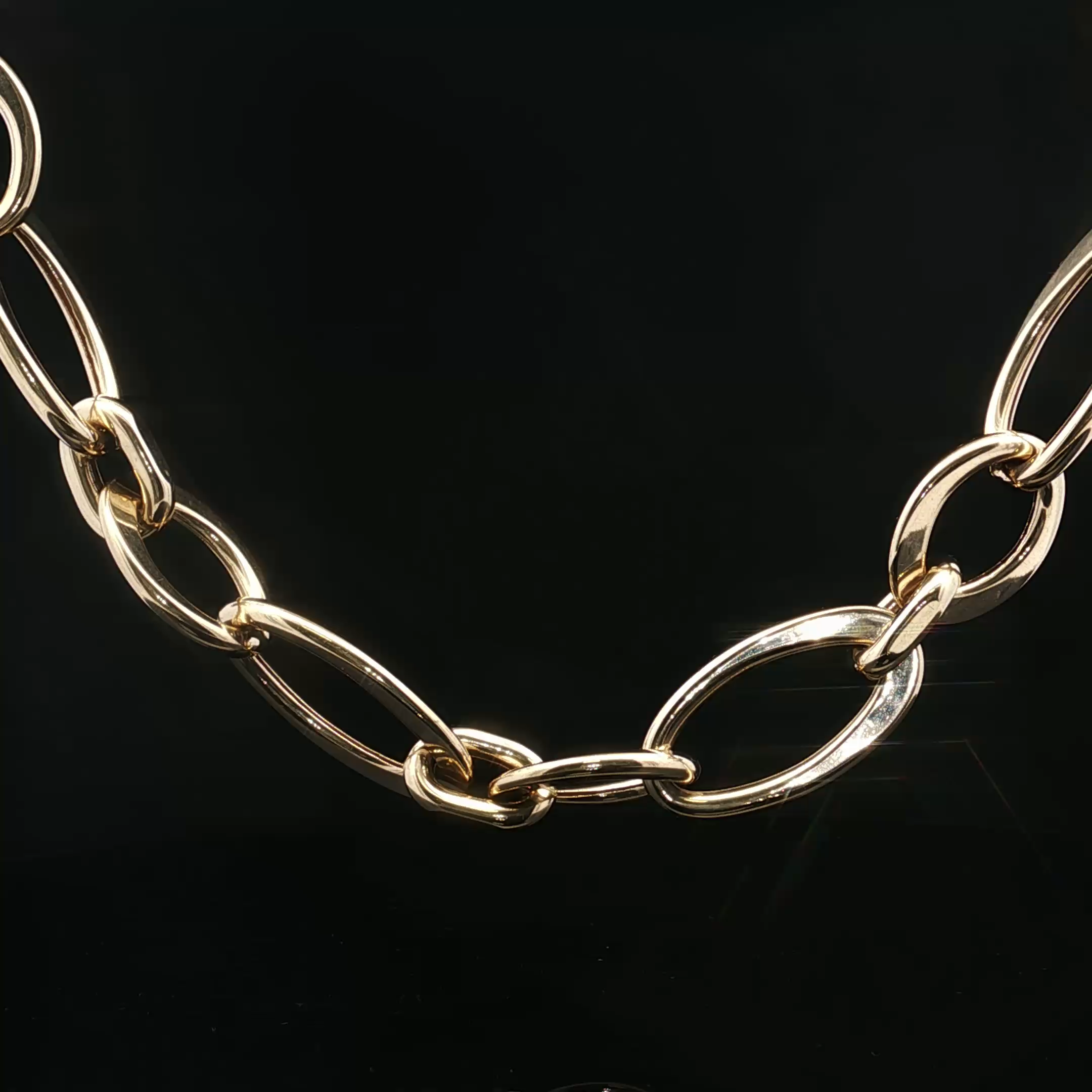 Close-up of shiny gold chain links on a black background.
