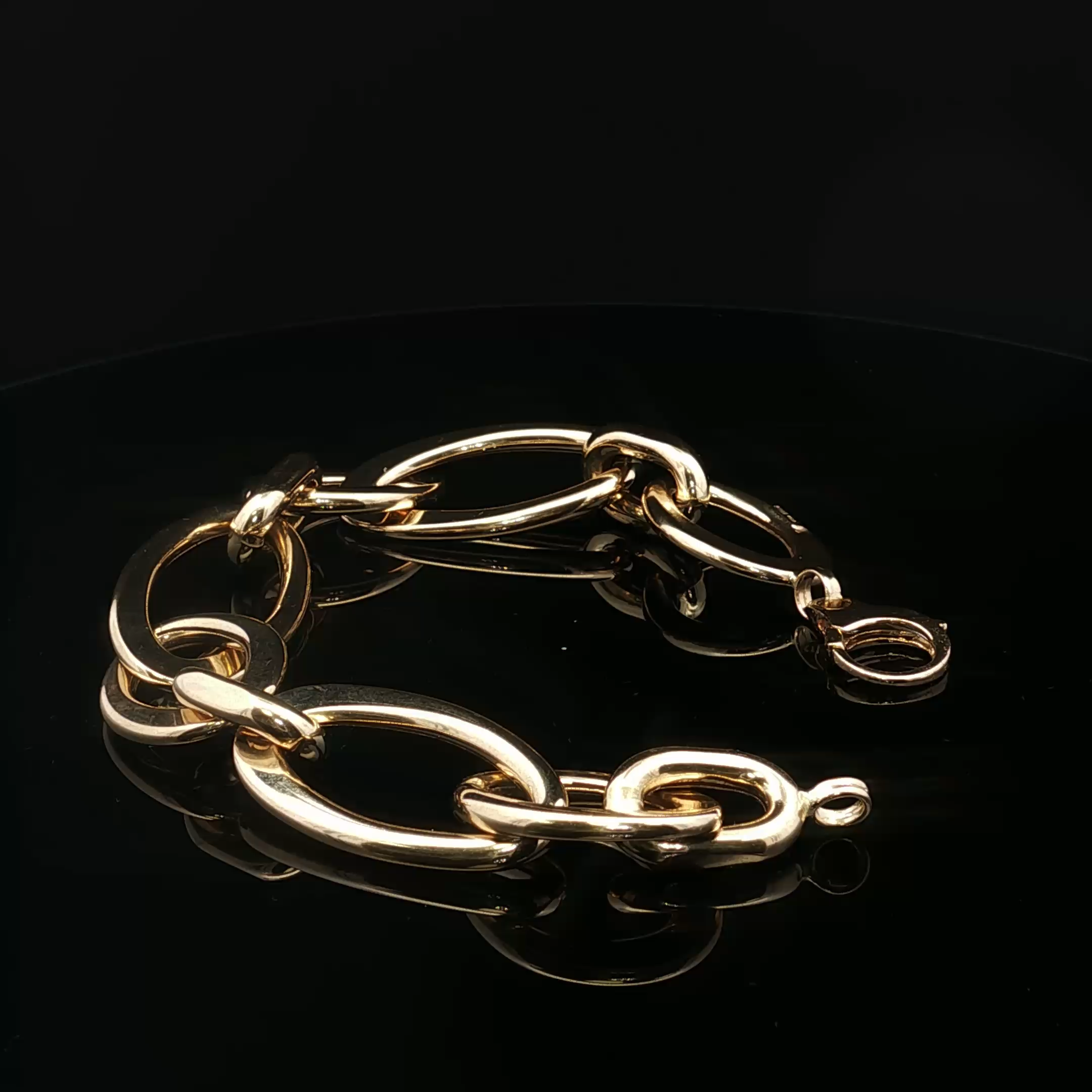 Close-up of gold-colored chain link bracelet against a black background.