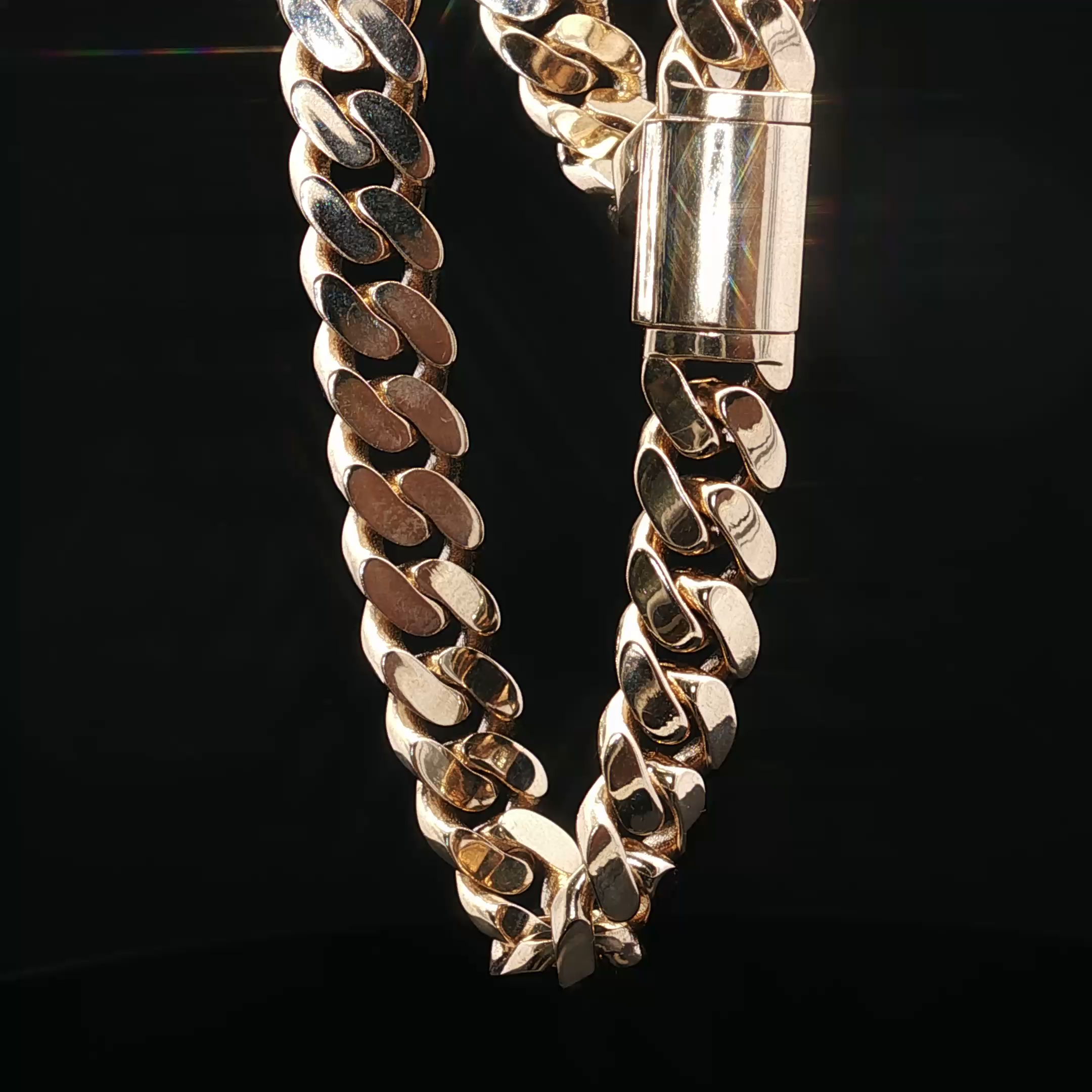 Close-up of a cuban chain with oval links, and a golden clasp font and center