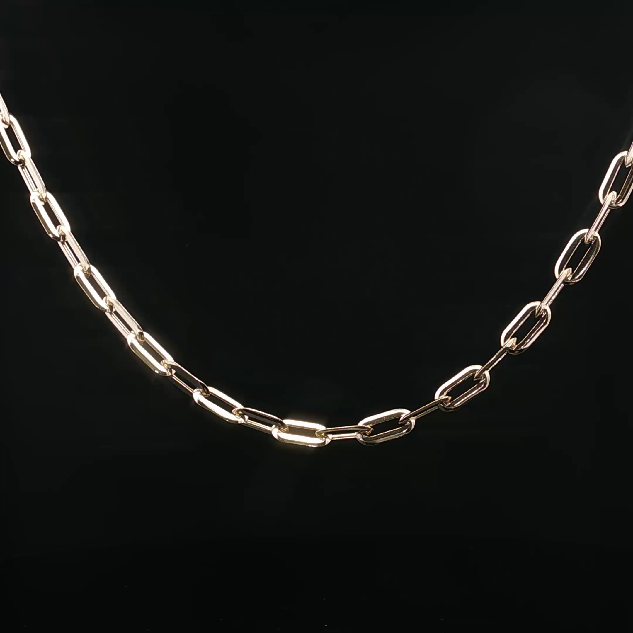 A white gold chain necklace with rectangular links is positioned against a black background.