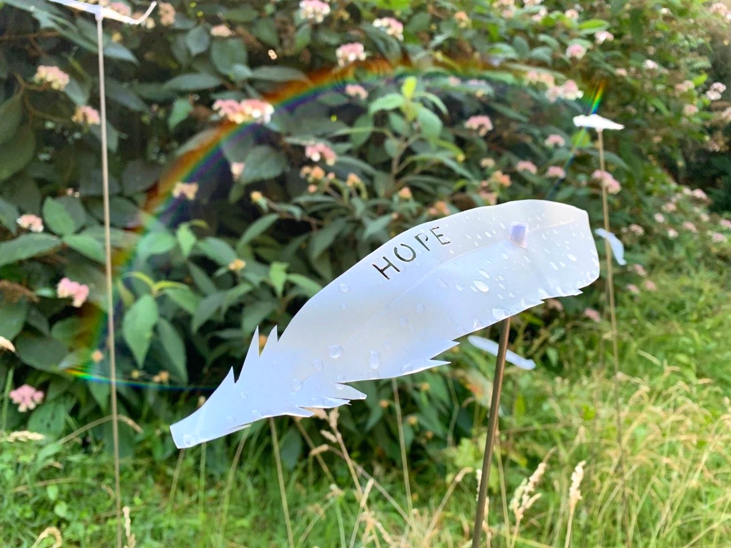 A white feather showing the word 'Hope' from 'A thousand feathers' by Studio Meraki exhibited at Stourhead.