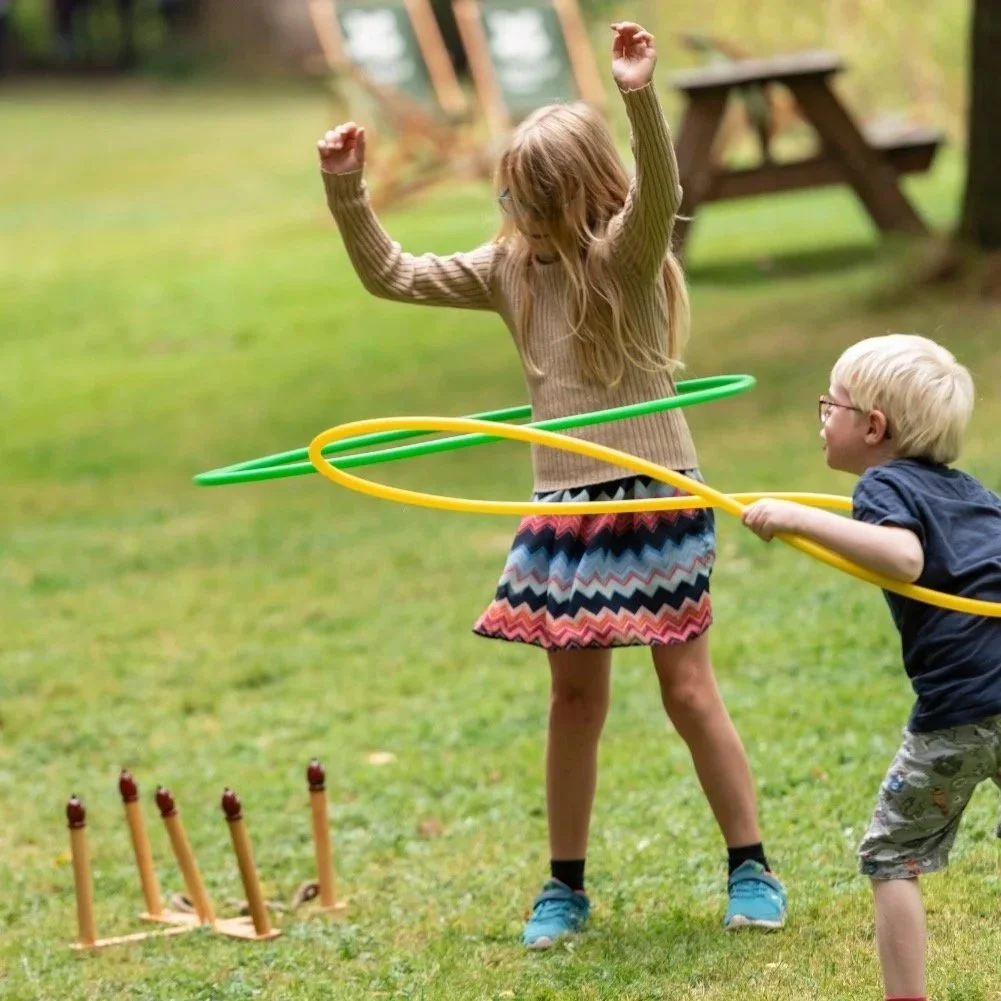 Two children play outside with hula hoops.