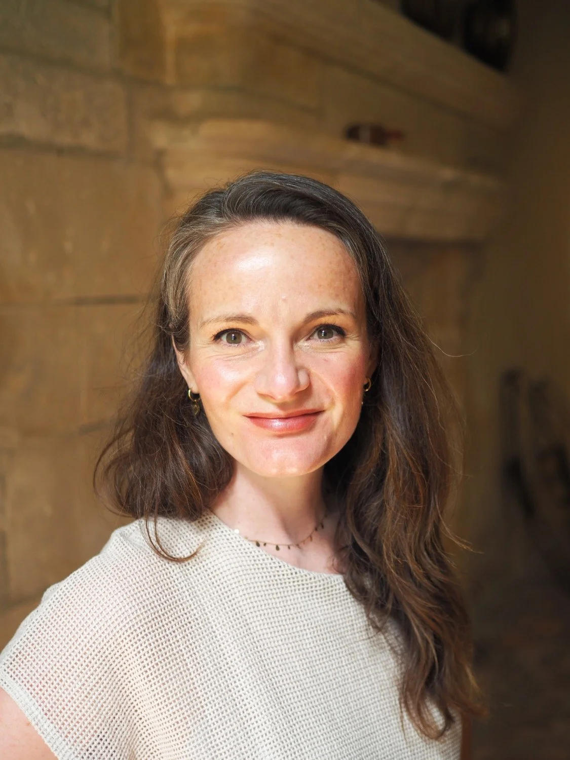 A portrait of Camilla Forest standing in front of a stone wall.