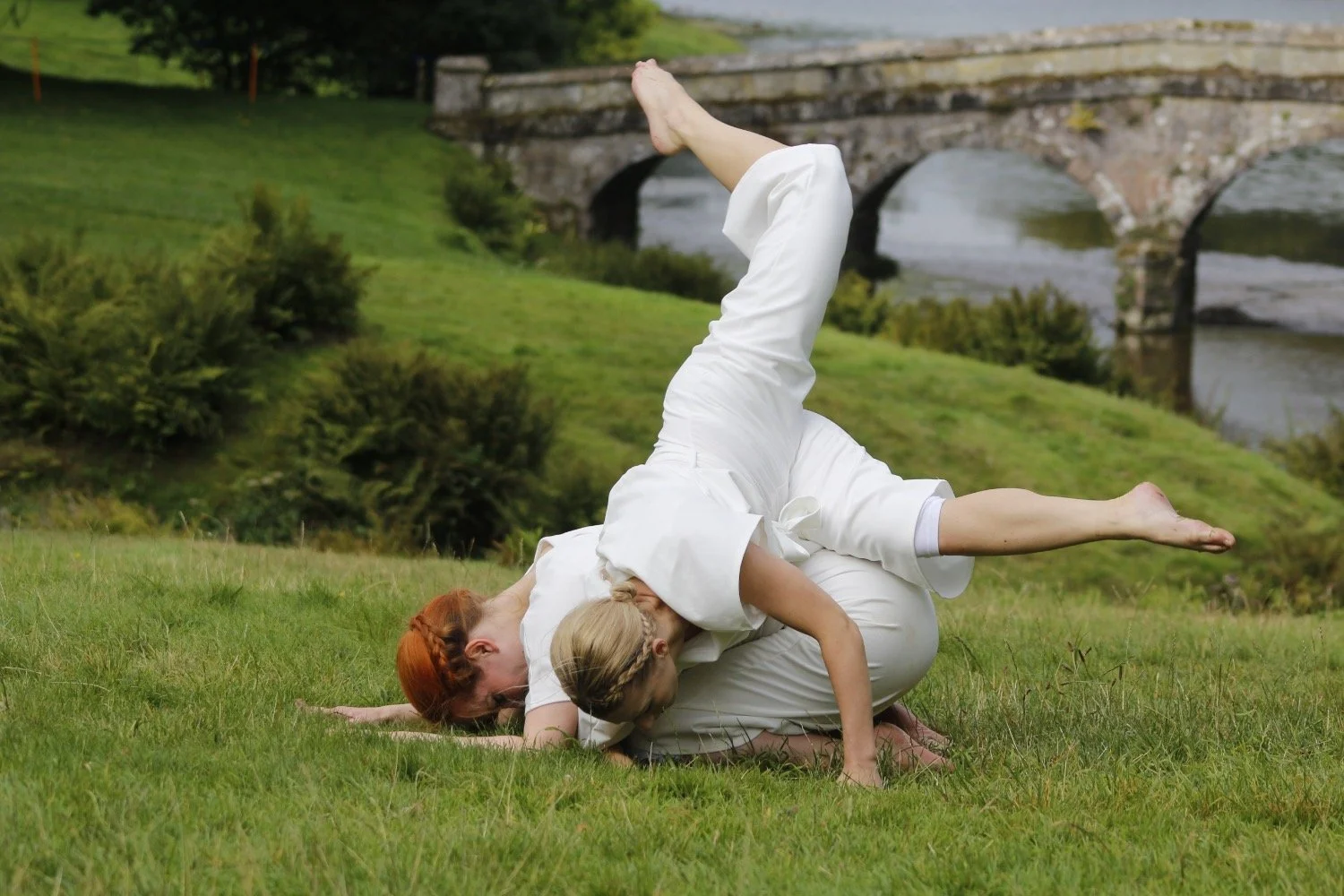 Two girls dance in front of the Palladian bridge at Stourhead.