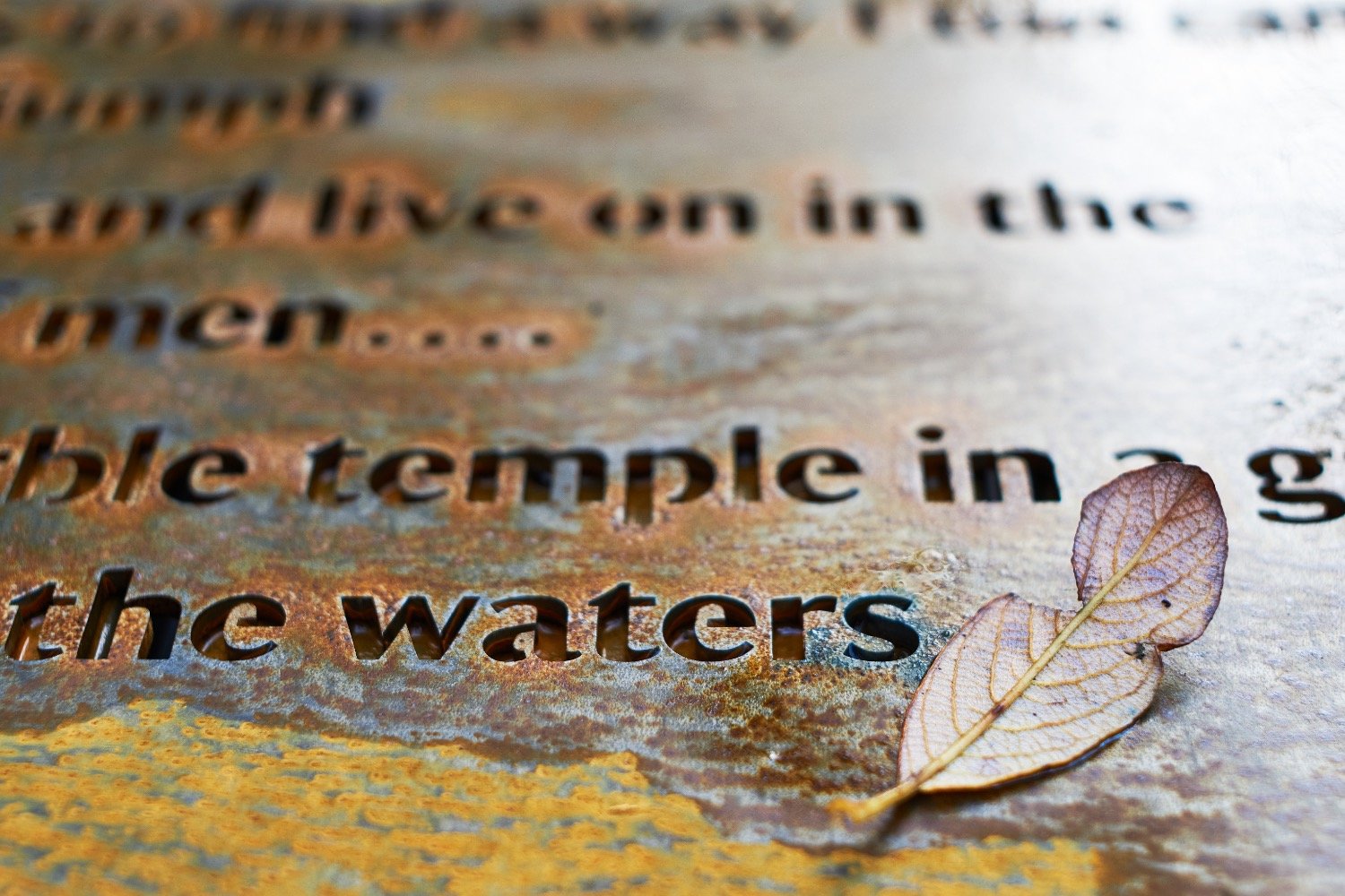 A section of a rusted steel panel showing words including 'temple' and 'waters'.