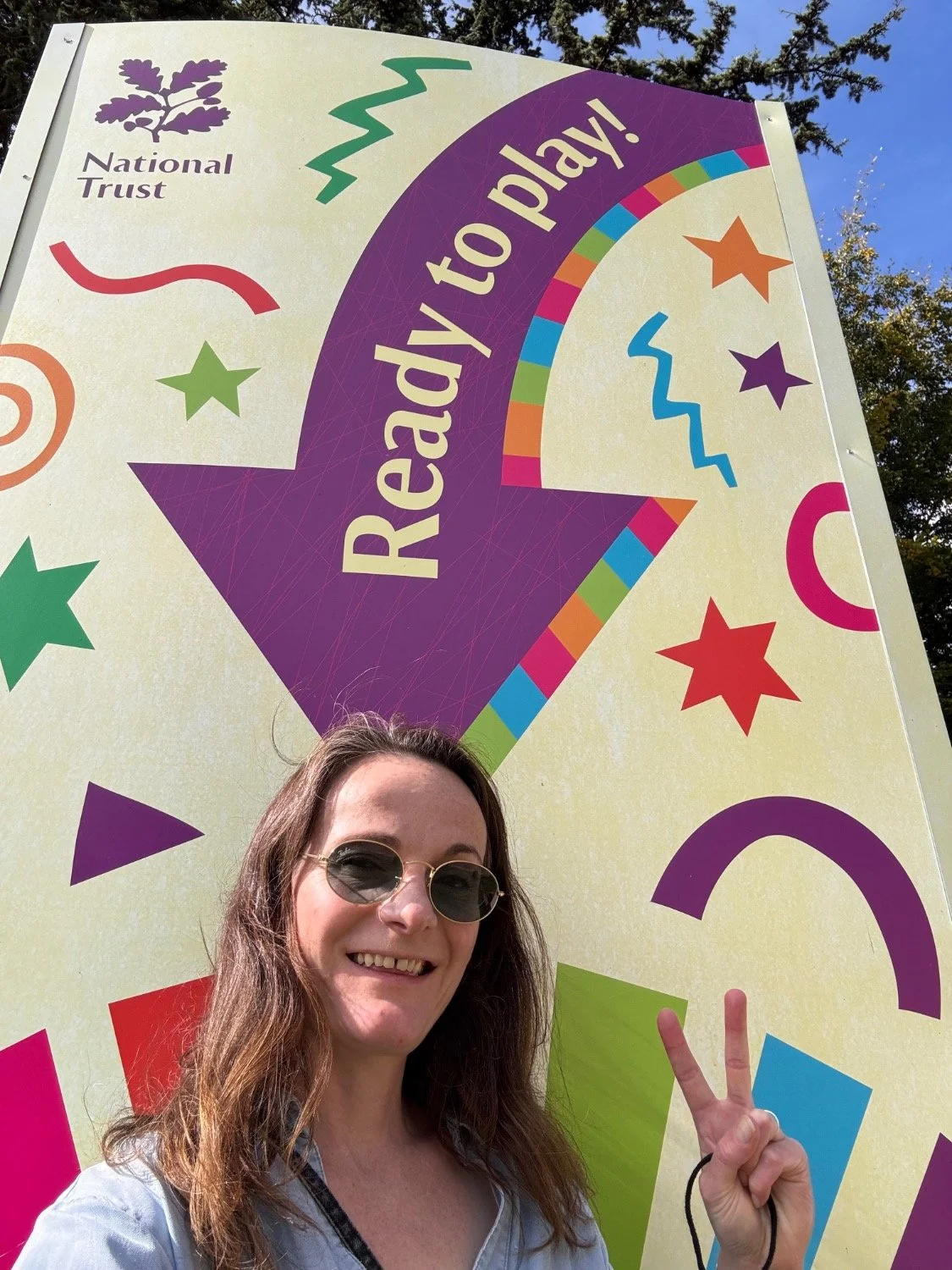 Camilla Forest stands in from of a Summer of Play poster that says 'Ready to play!'