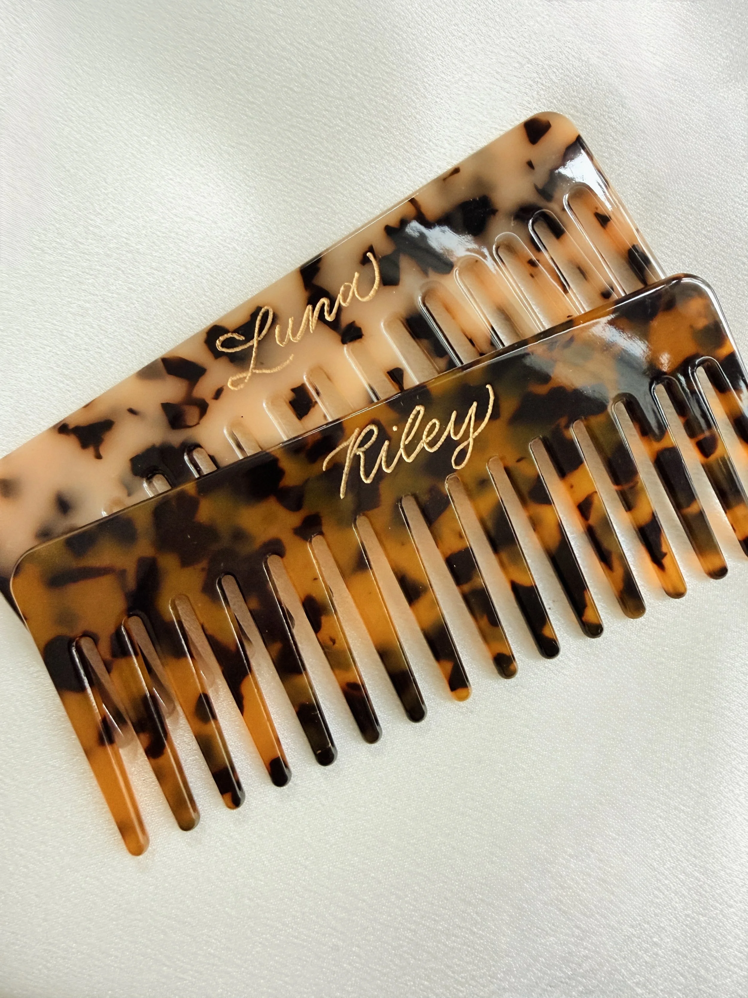 Two tortoise shell hair combs with gold cursive engraved names, one labeled 'Lindsay' and the other 'Riley'.