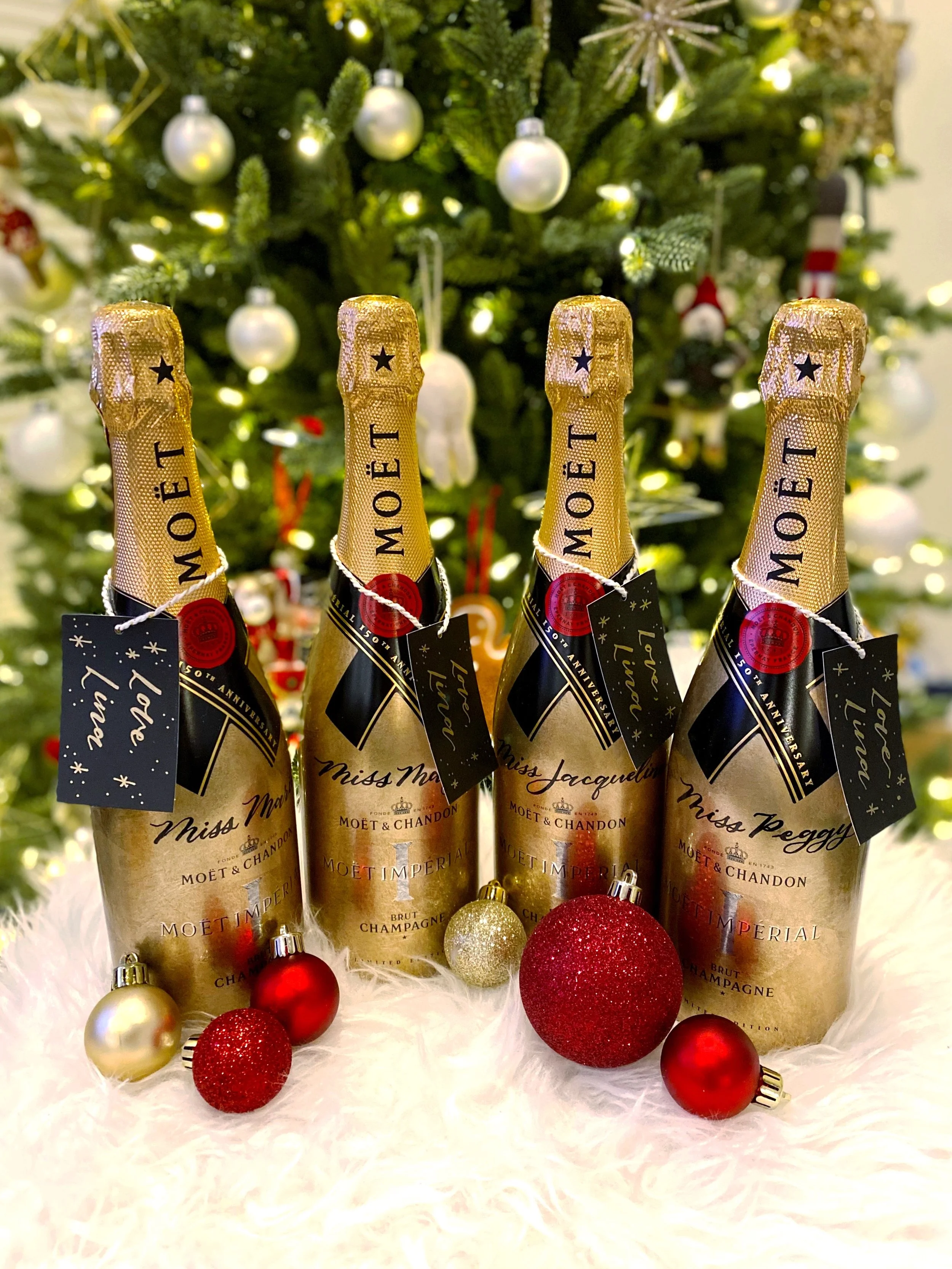 Personalized champagne bottles with hand-lettered ribbon tags for luxury holiday gifting and custom calligraphy services