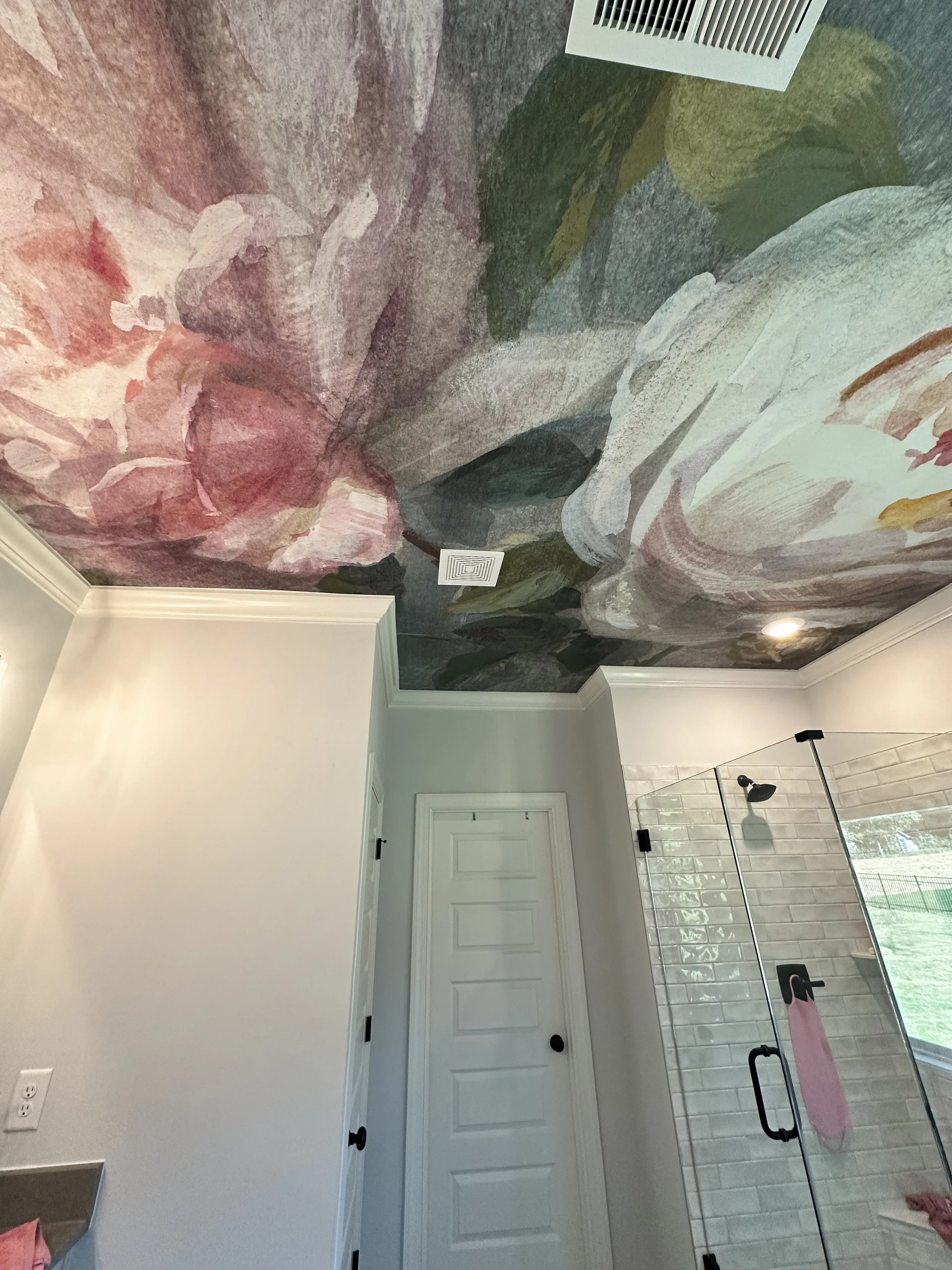 The ceiling of a bathroom painted with a large, abstract floral mural featuring pink, white, green, and gray colors.