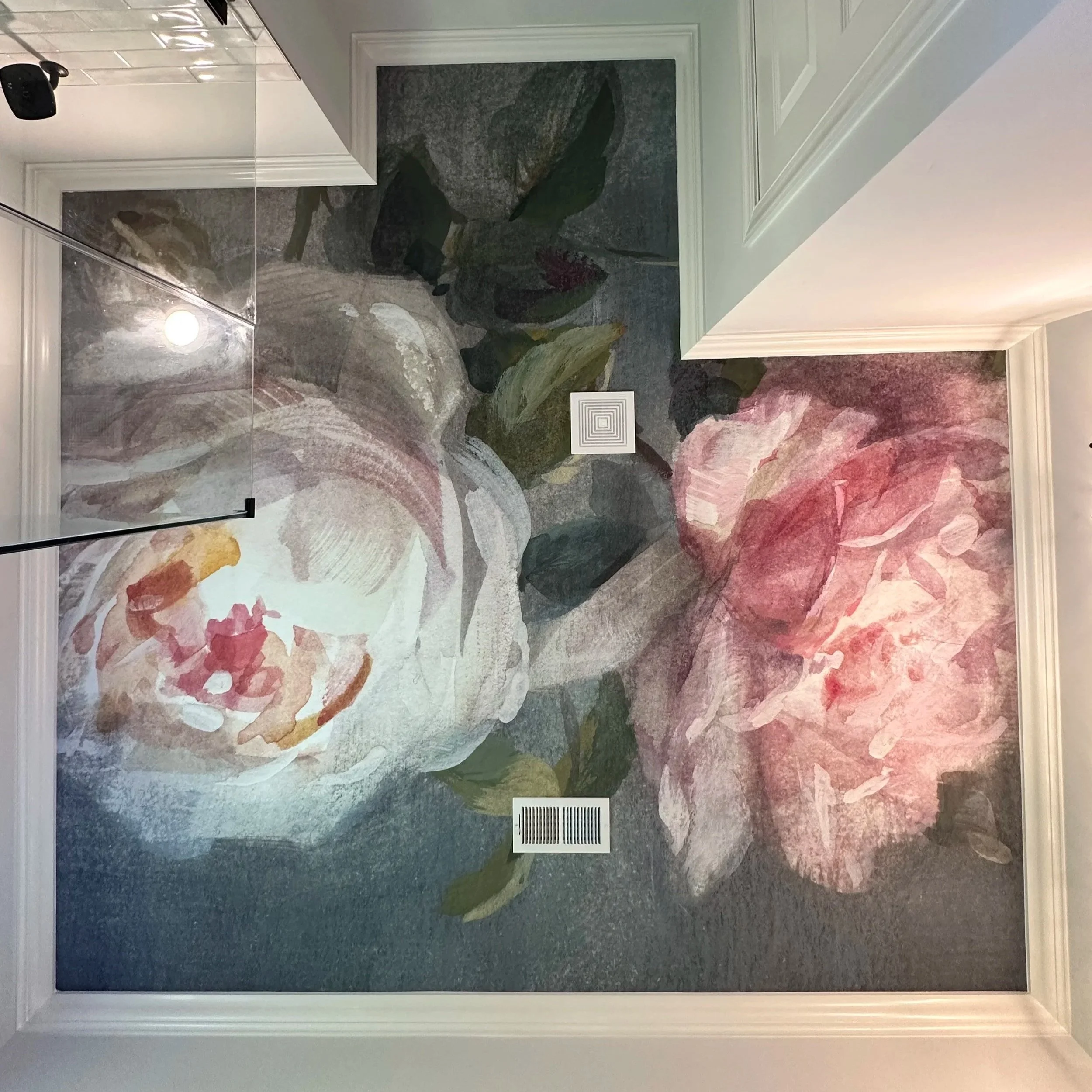 Wall mural of large pink and white flowers with green leaves in a living room.