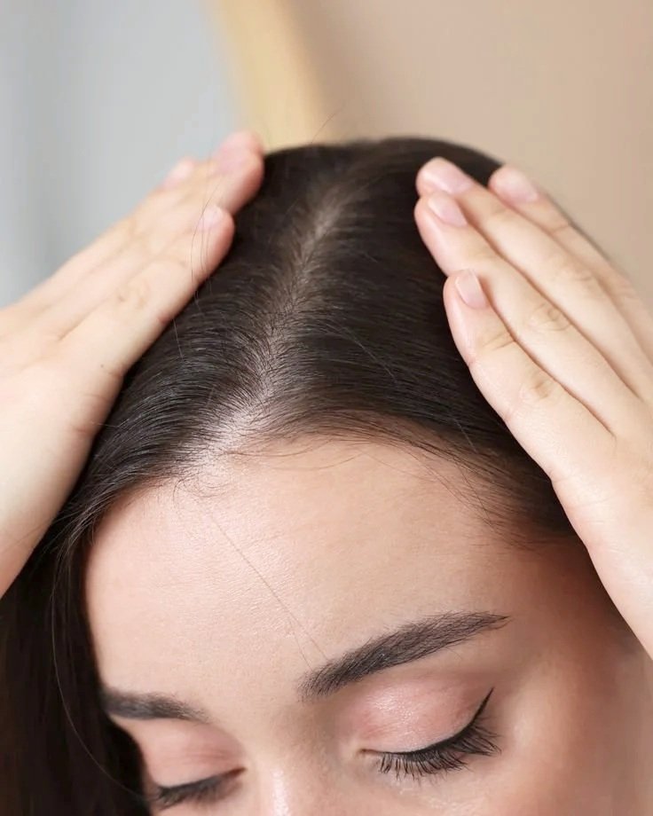 Woman examining her scalp during a professional hair and scalp assessment at Ottawa hair restoration clinic