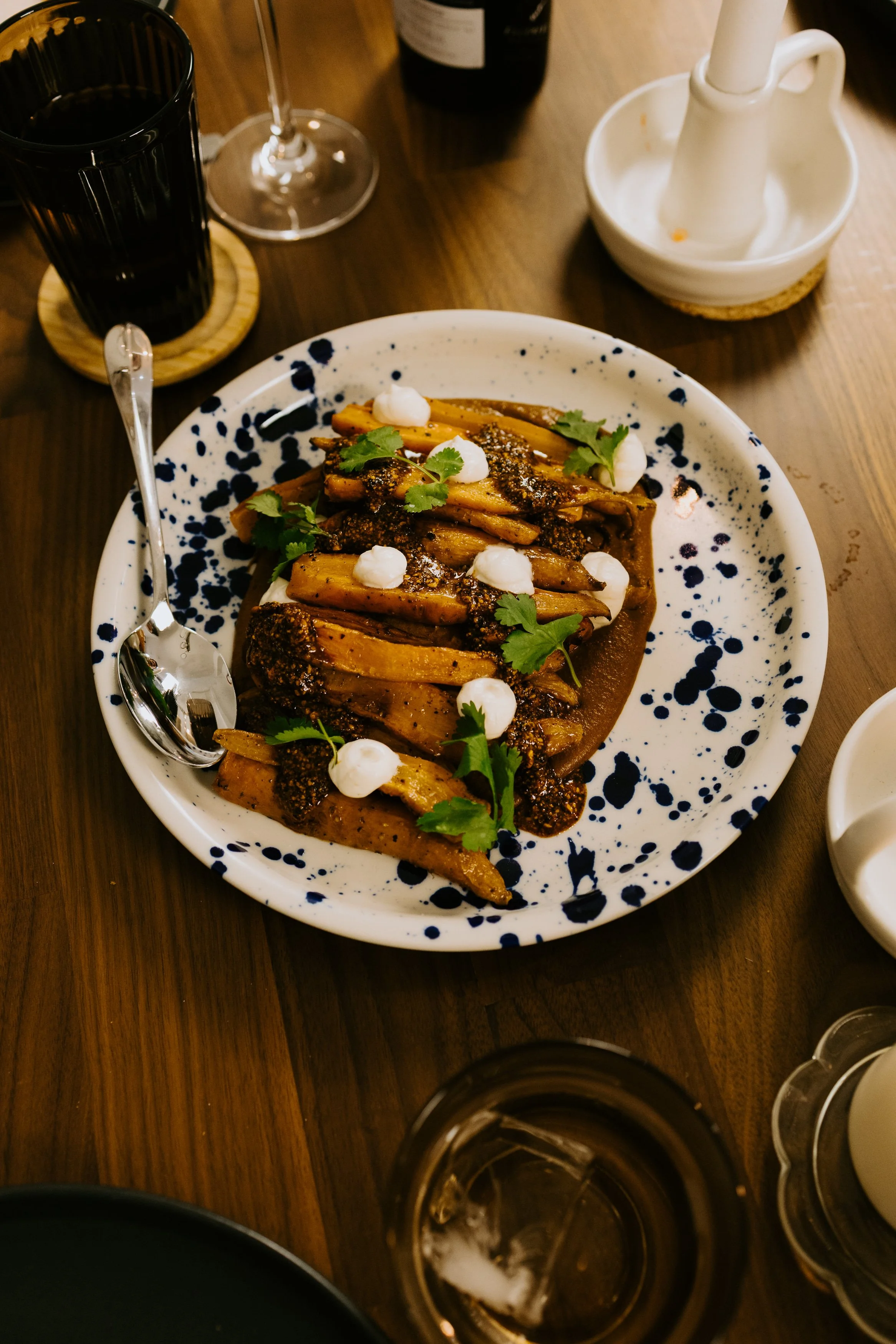 Plate of roasted cauliflower garnished with herbs, cream dollops, and spices, served on a splatter-patterned white and black plate.