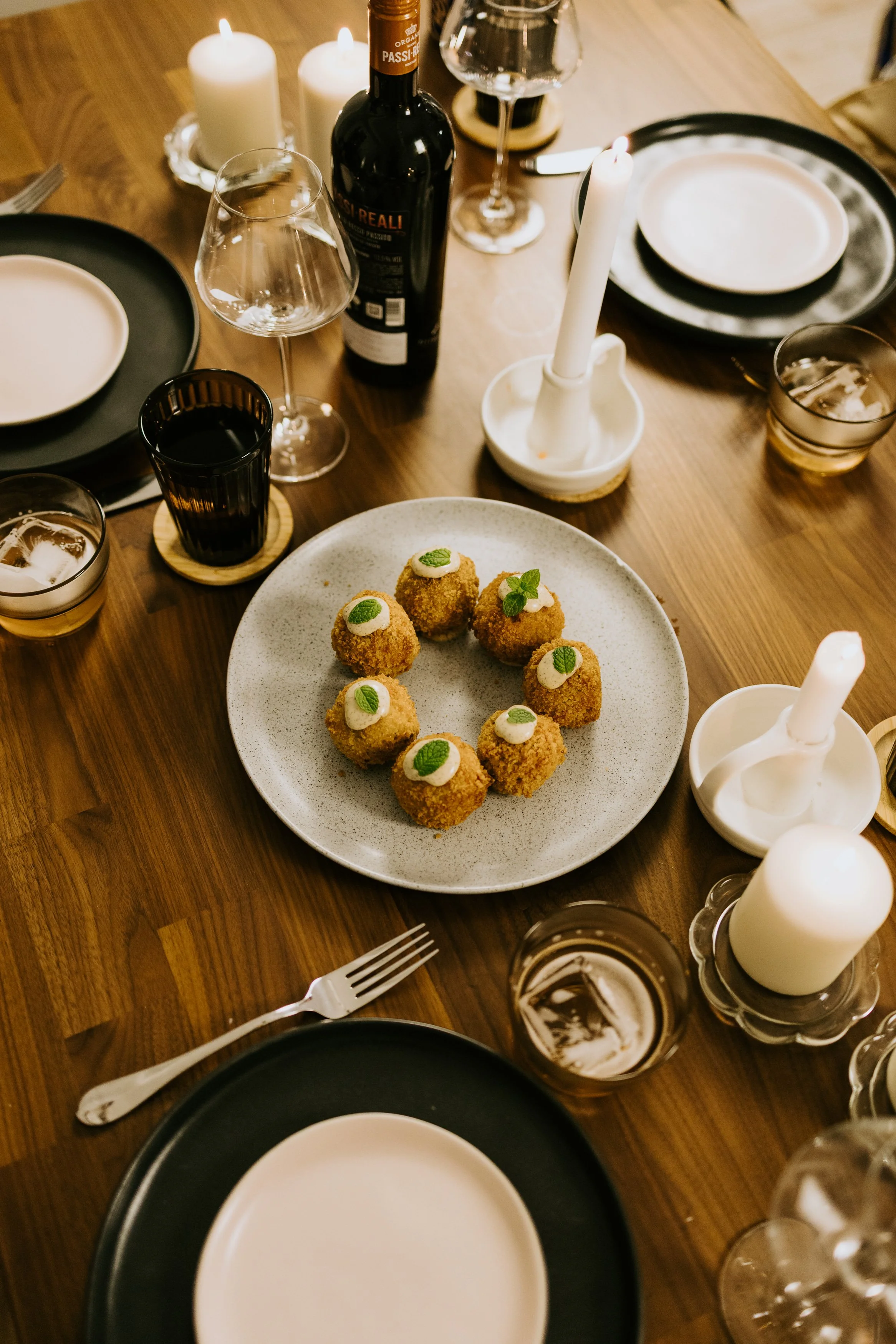 Mountain range with snow-capped peaks in background, rolling green and brown hills in foreground, and a modern building on the hillside.