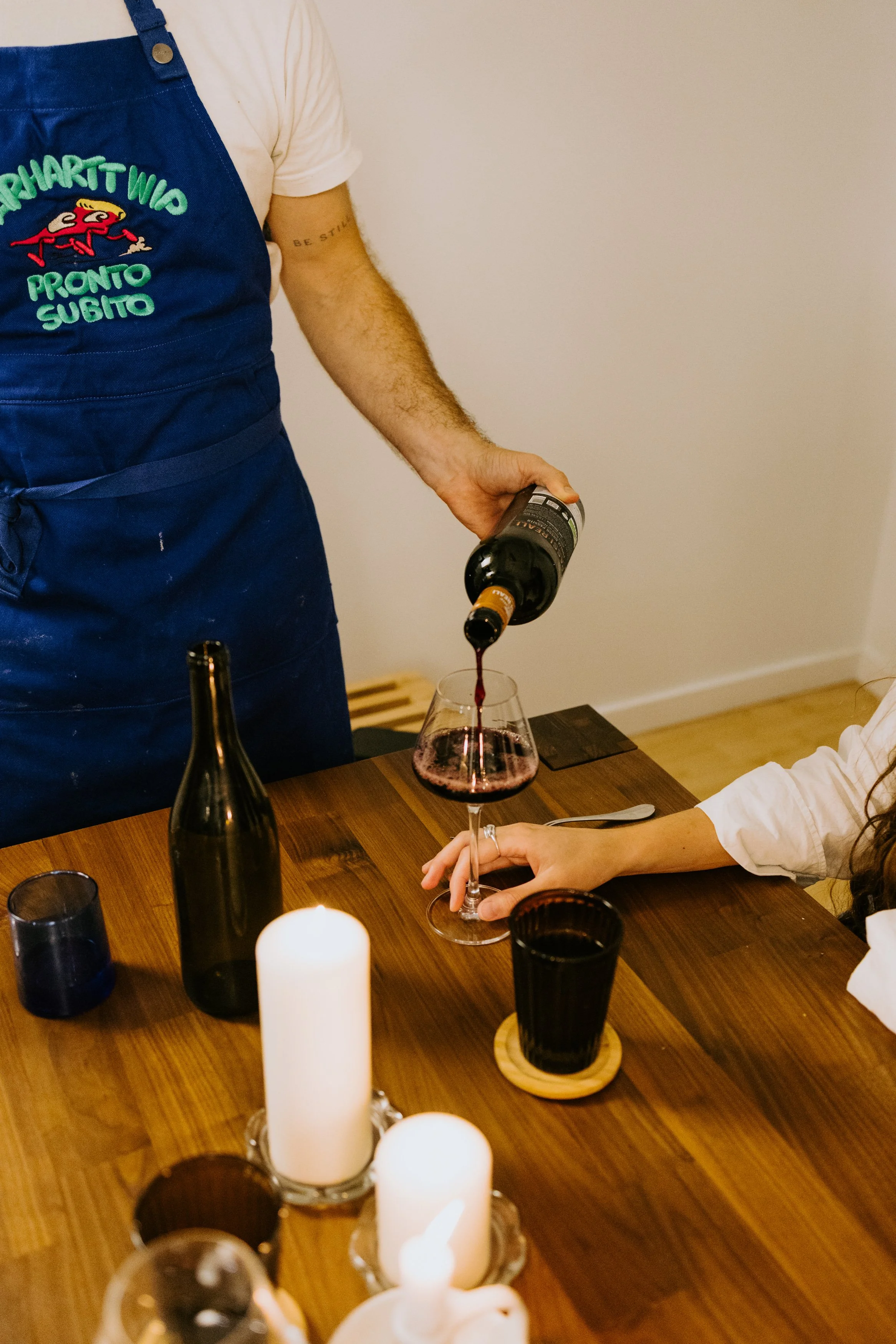 A landscape of mountains with a lake in the foreground and grassy hills, under a cloudy sky.