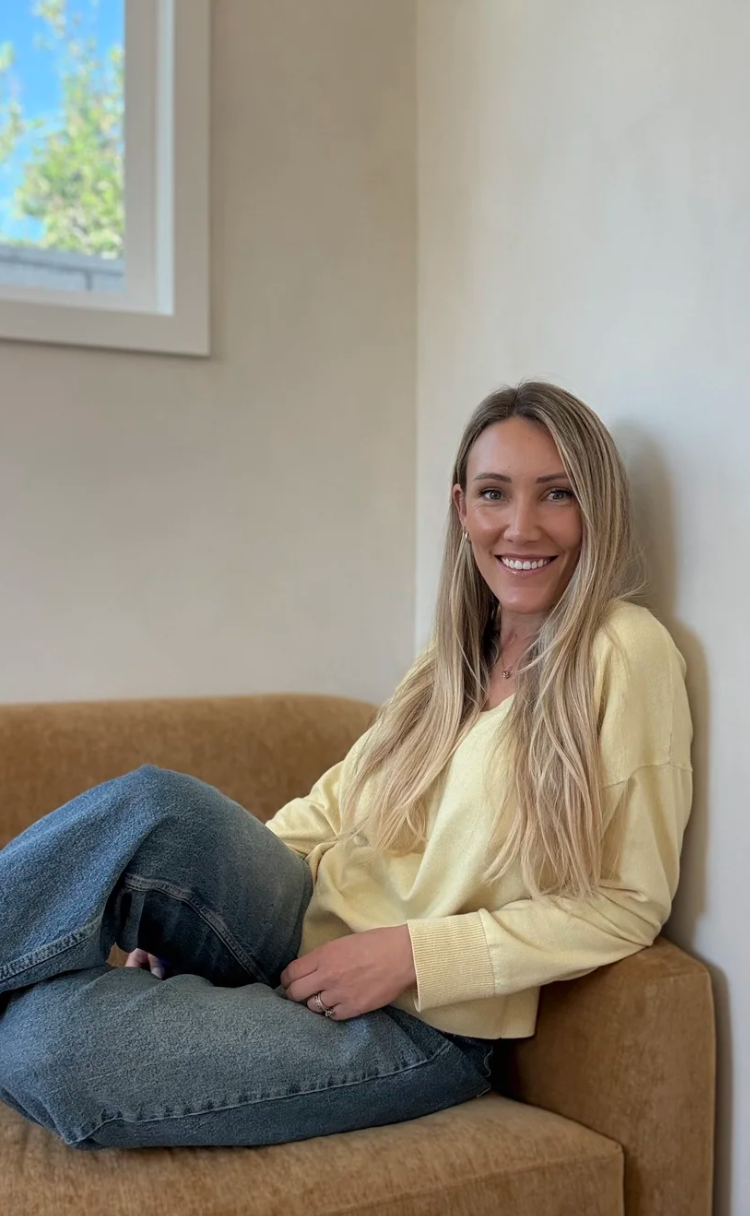 Woman with blonde hair sitting on a couch in a therapy office.