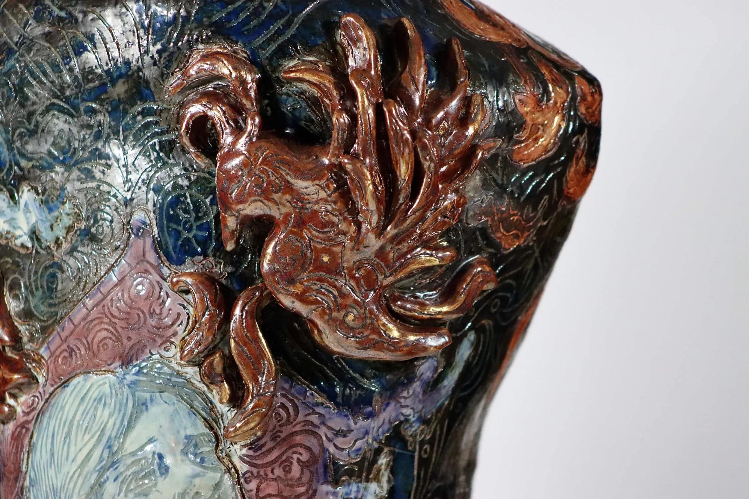 “Rebirth”, 2025. Red stoneware clay with sgraffitto,  black and porcelain slips, malcolm shino, red irwing, peach bloom 2, cuba's beaches, purple haze, and gold acrylic paint.
9" x 23" inches. 
The ceramic vase displays a narrative story of rising fr