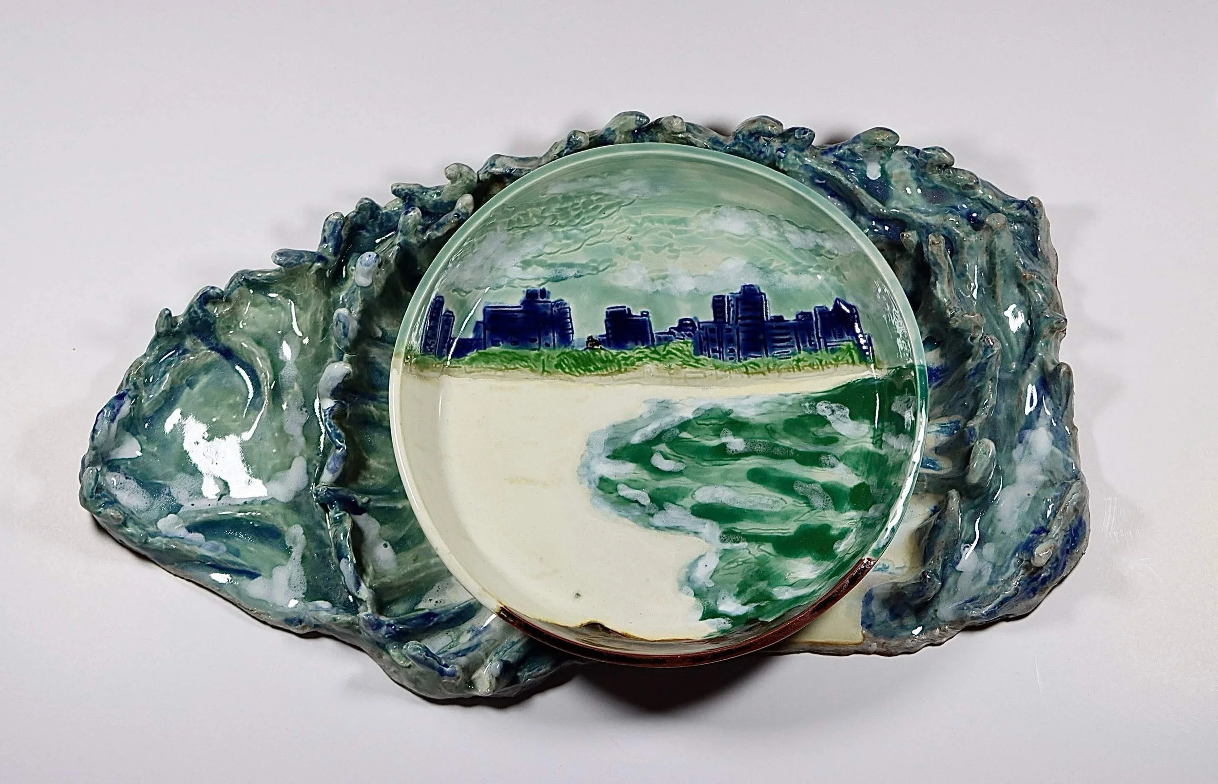"My Rushing Waves of Culture III" 2026.  Glazed Porcelain. 11" x 8" inches.  Part of a series.  A ceramic plate of Miami Beach's shoreline on a tray in the form of ocean waves.