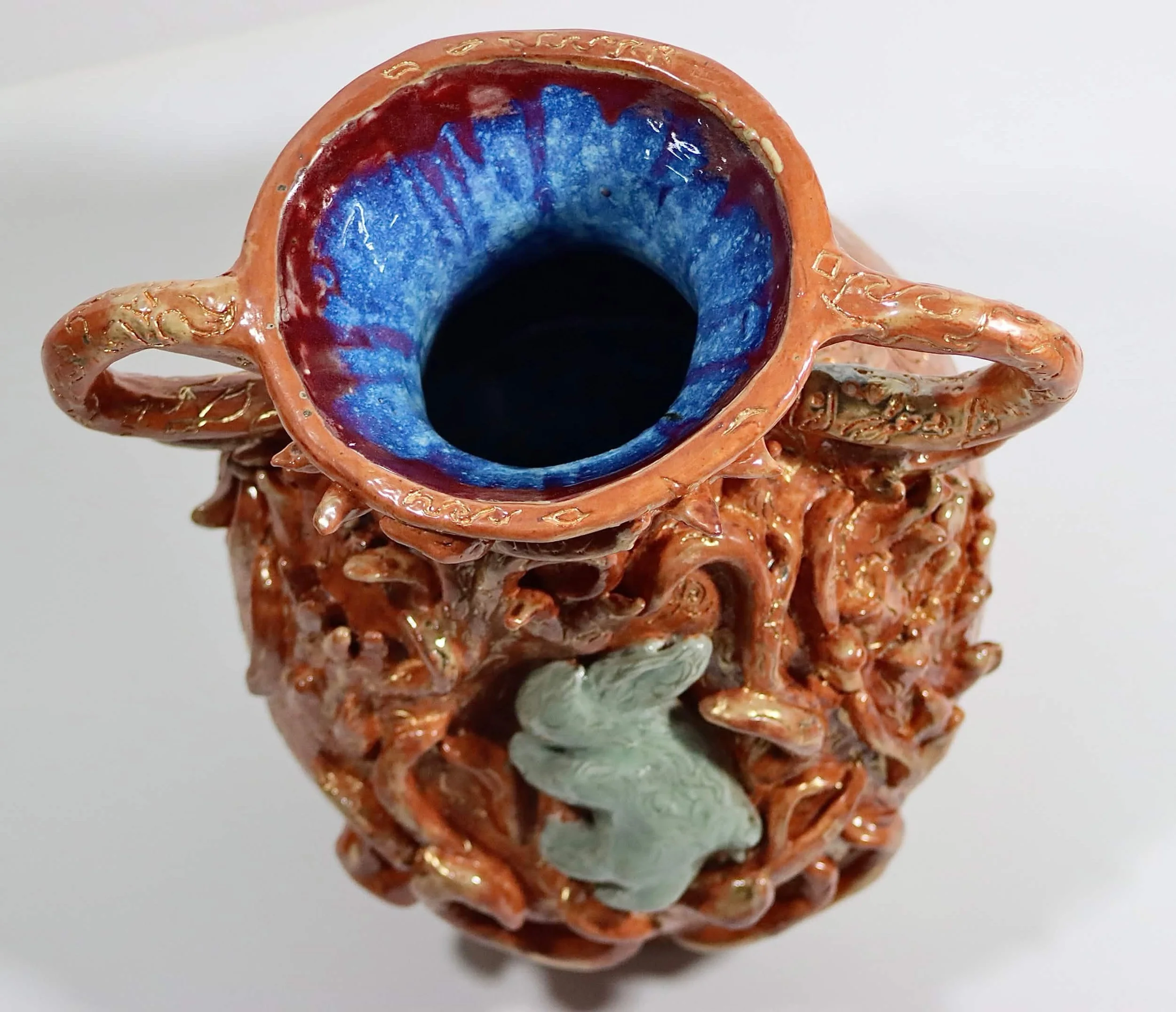 "Frail Spirit Burning Brighter", 2026. Glazed Red Stoneware with porcelain slip and acrylic paint. 9" x 16" inches. A ceramic vessel entails a docile soul in the form of a rabbit spreading its luminous flames. 