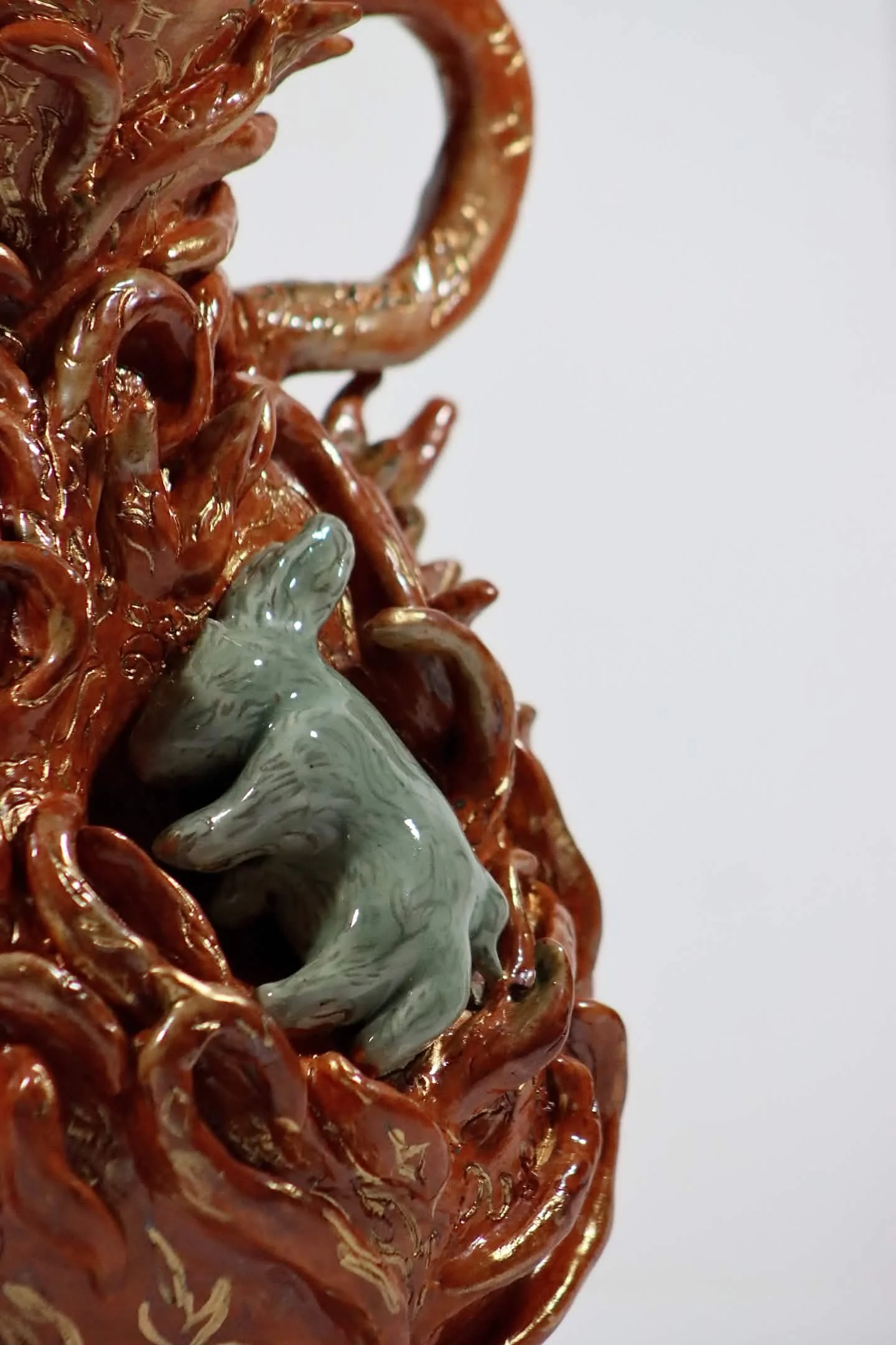"Frail Spirit Burning Brighter", 2026. Glazed Red Stoneware with porcelain slip and acrylic paint. 9" x 16" inches. A ceramic vessel entails a docile soul in the form of a rabbit spreading its luminous flames. 
