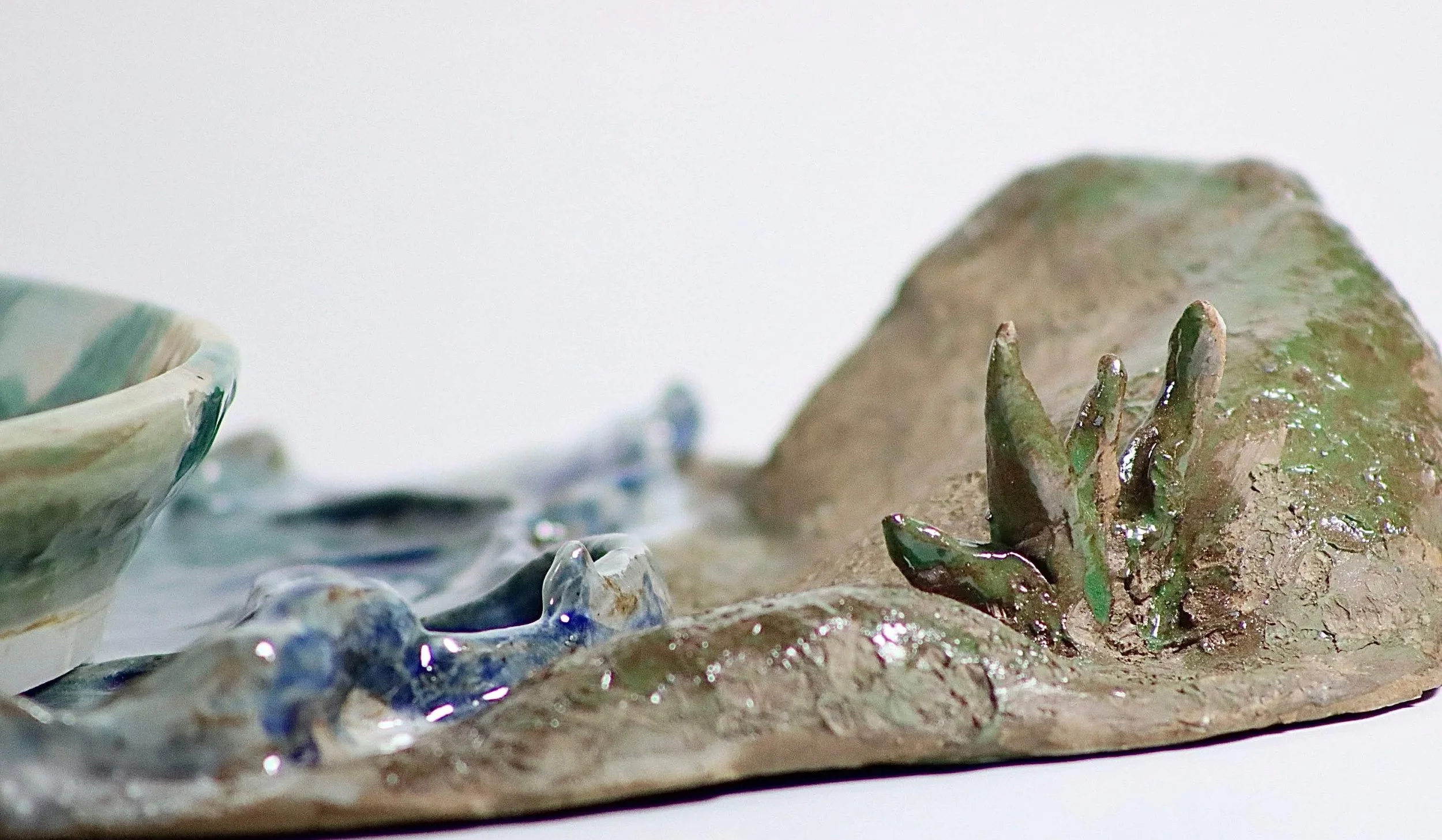 "My Rushing Waves of Culture II", 2026. Glazed Red Stoneware and Porcelain. 10.75" x 8.25" inches.

 Part of a series . A ceramic plate with a tray in the form of a lake showcasing my mother in San Jose, Peru cradling a sheep.