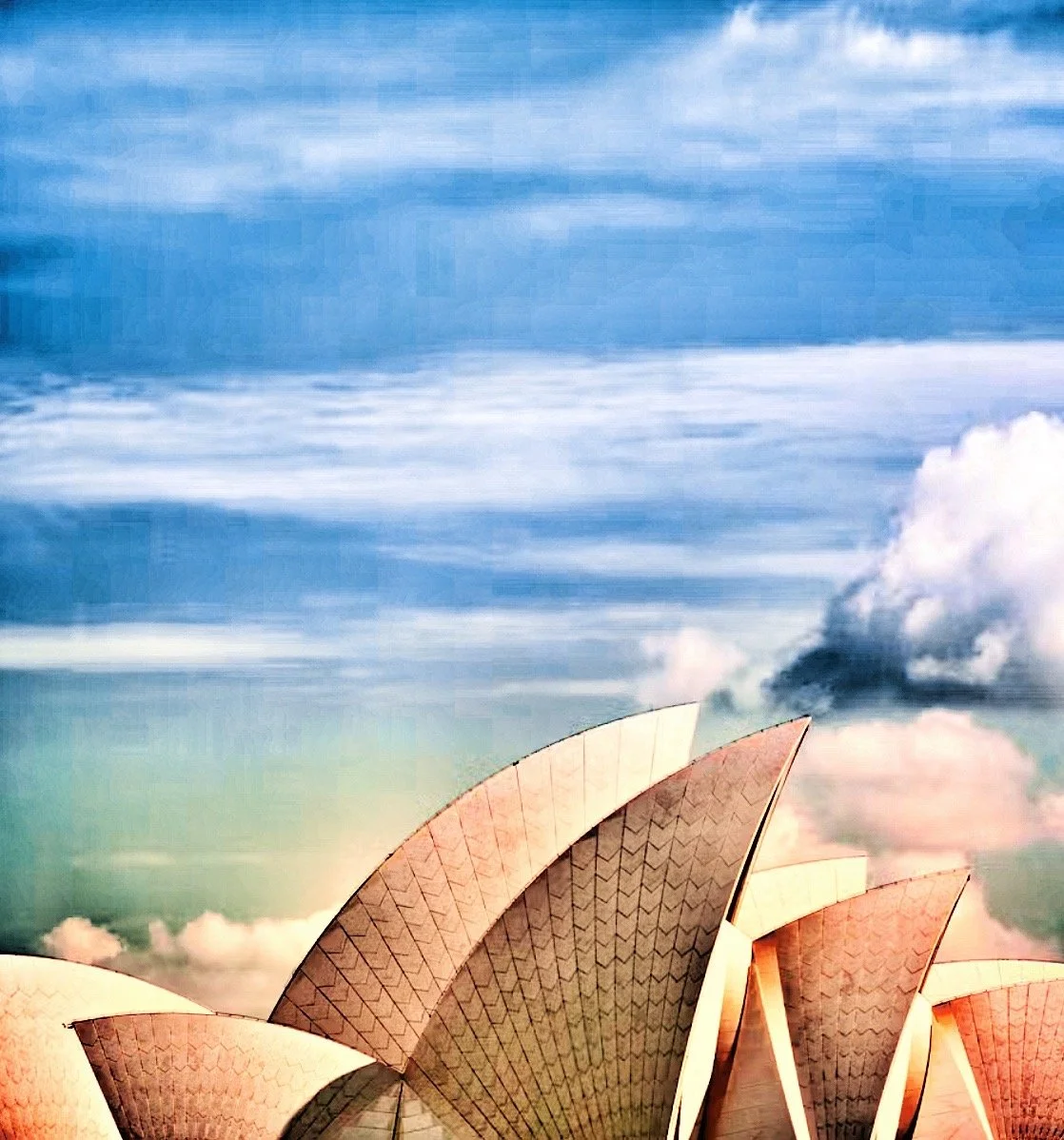 Close-up of the Sydney Opera House with a partly cloudy sky background.