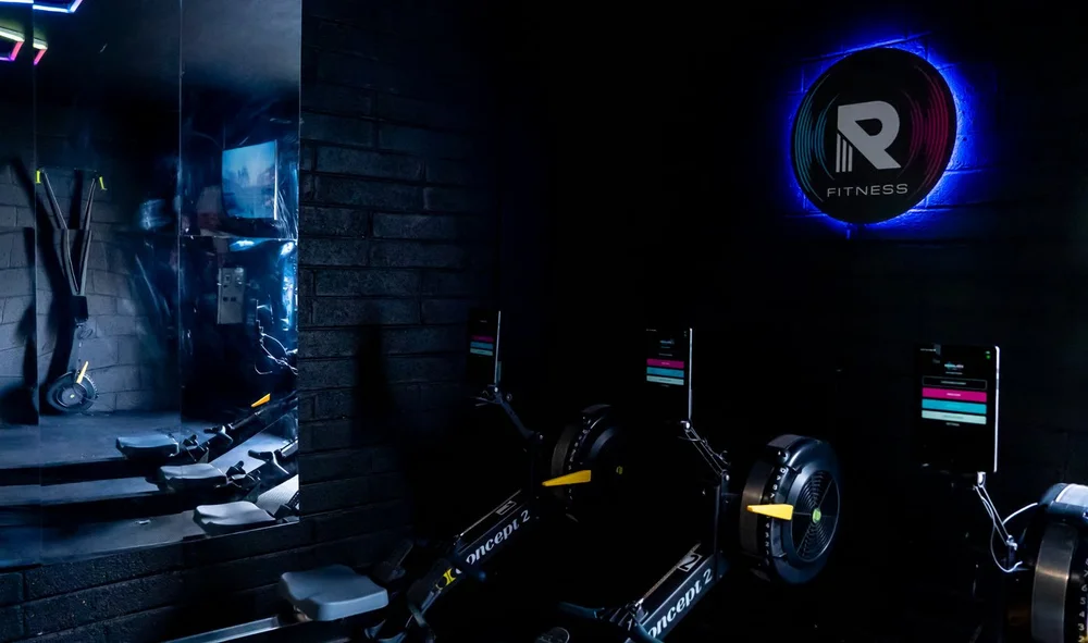 The Revelate room at The Engine Room: Concept 2 rowers lined up under the lit R logo.