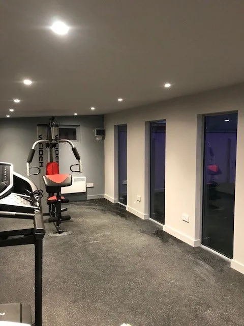 Personal training empty gym room with treadmill and exercise machine, large double glazed windows, and recessed led ceiling lights. Making working from home extremely easy with Barna Buildings home-gym.