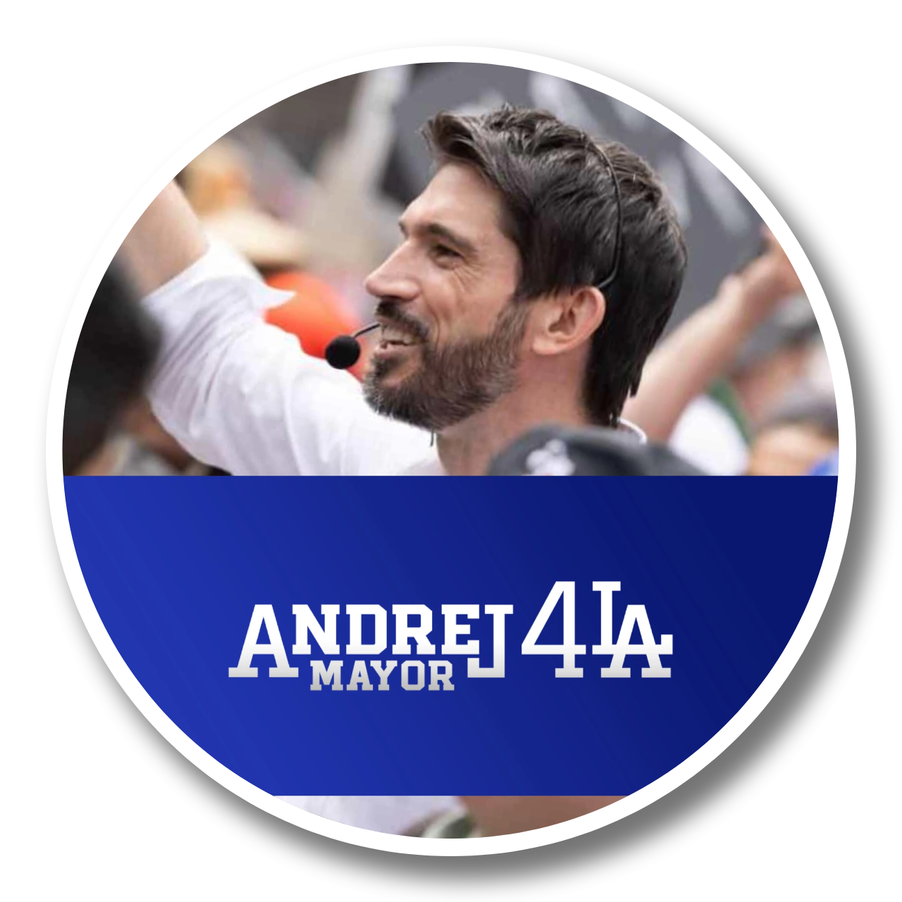 A man with dark hair and a beard wearing a white shirt using a headset microphone, smiling at a rally or event with a crowd in the background, promoting Andrew Yang for mayor.