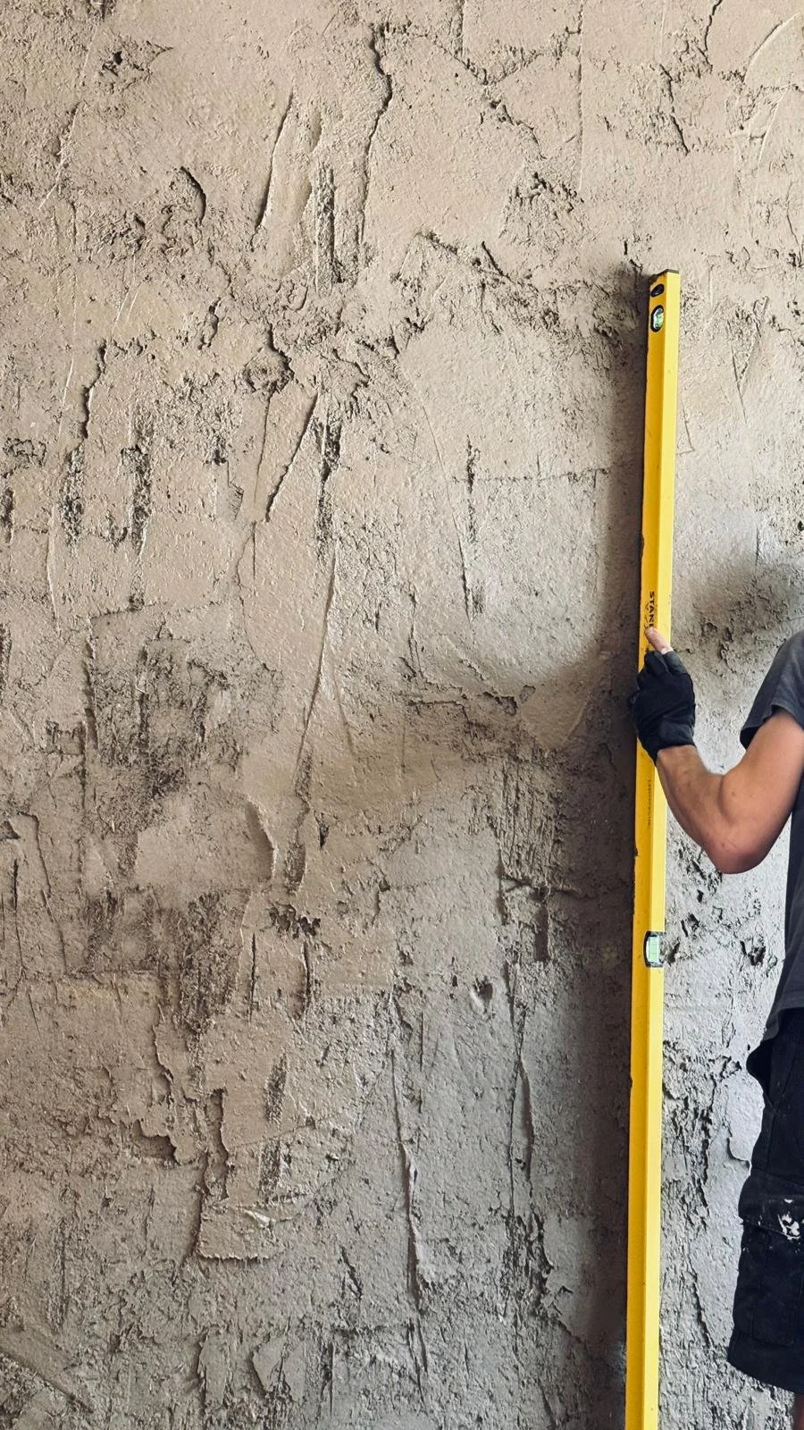 Praktijkworkshop leemstuc waarbij leem op een muur wordt aangebracht