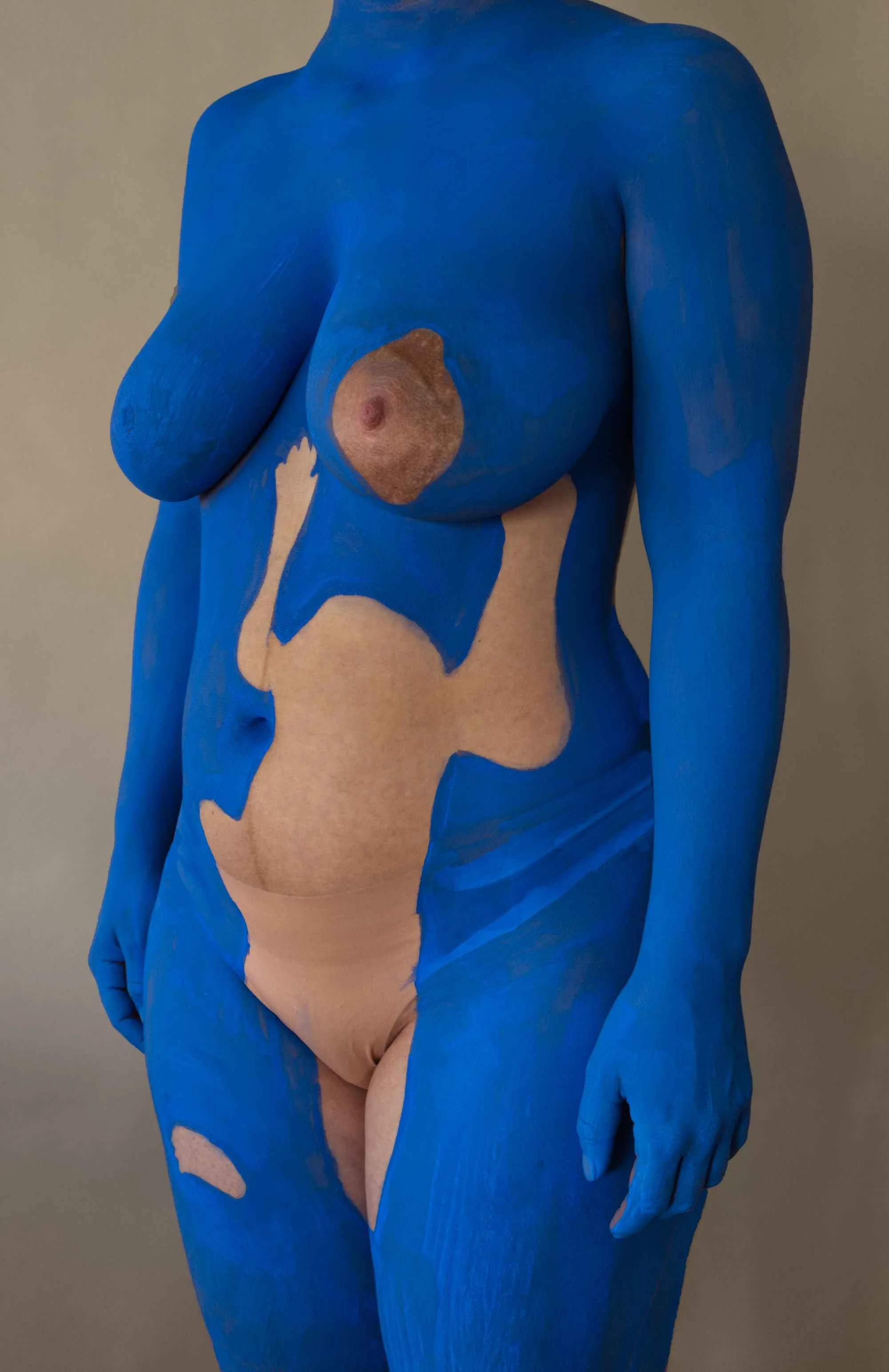 A woman with her body painted in blue with natural skin visible on her chest, waist, and parts of her arms and legs.