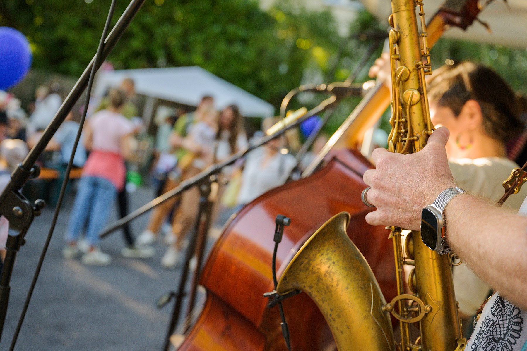 Ein Musiker spielt Saxophon während des Quartierfest Elfenau in Bern. Einer Gruppe von Menschen im Hintergrund.