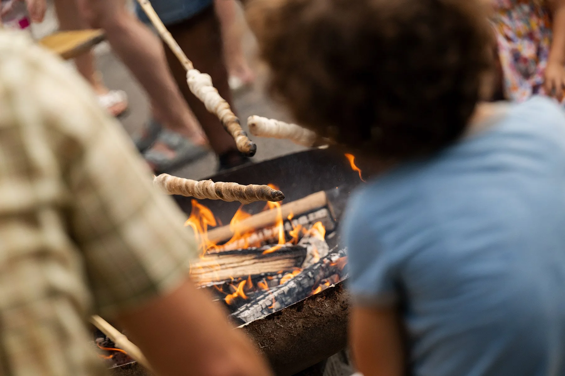 Menschen, die auf einem Grill mit Flammen Brot oder Teigwaren backen.