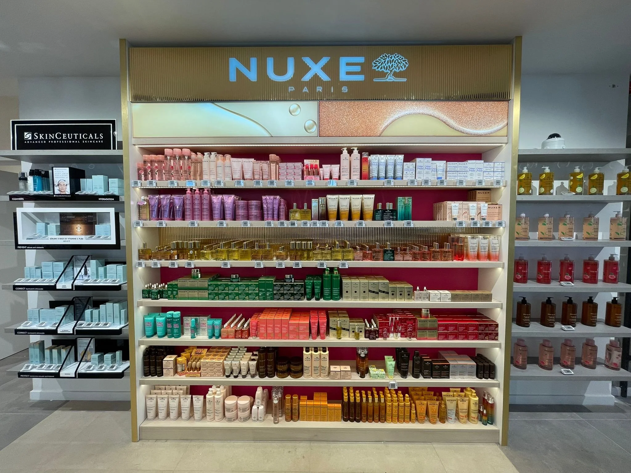 Display shelves stocked with Nuxe skincare products in a store, featuring various creams, serums, and oils in colorful packaging.
