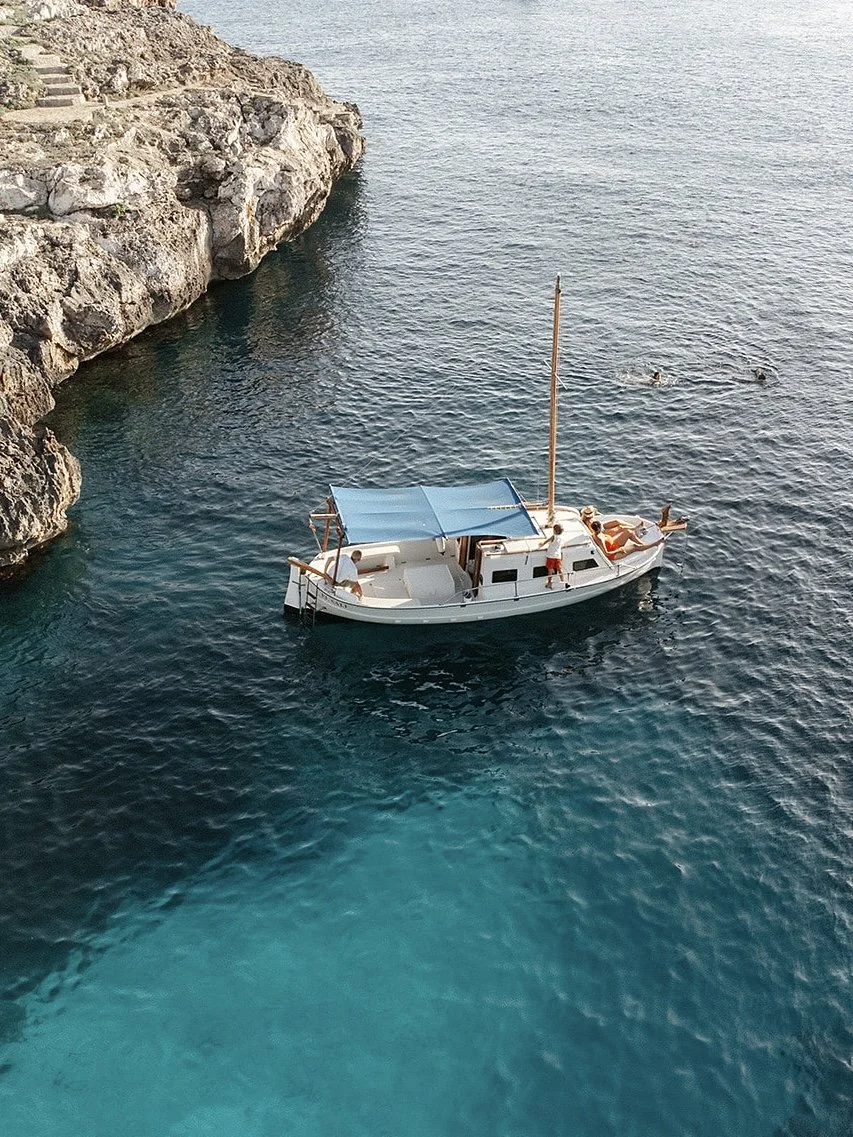 Traditional boat anchored in a cove in menorca