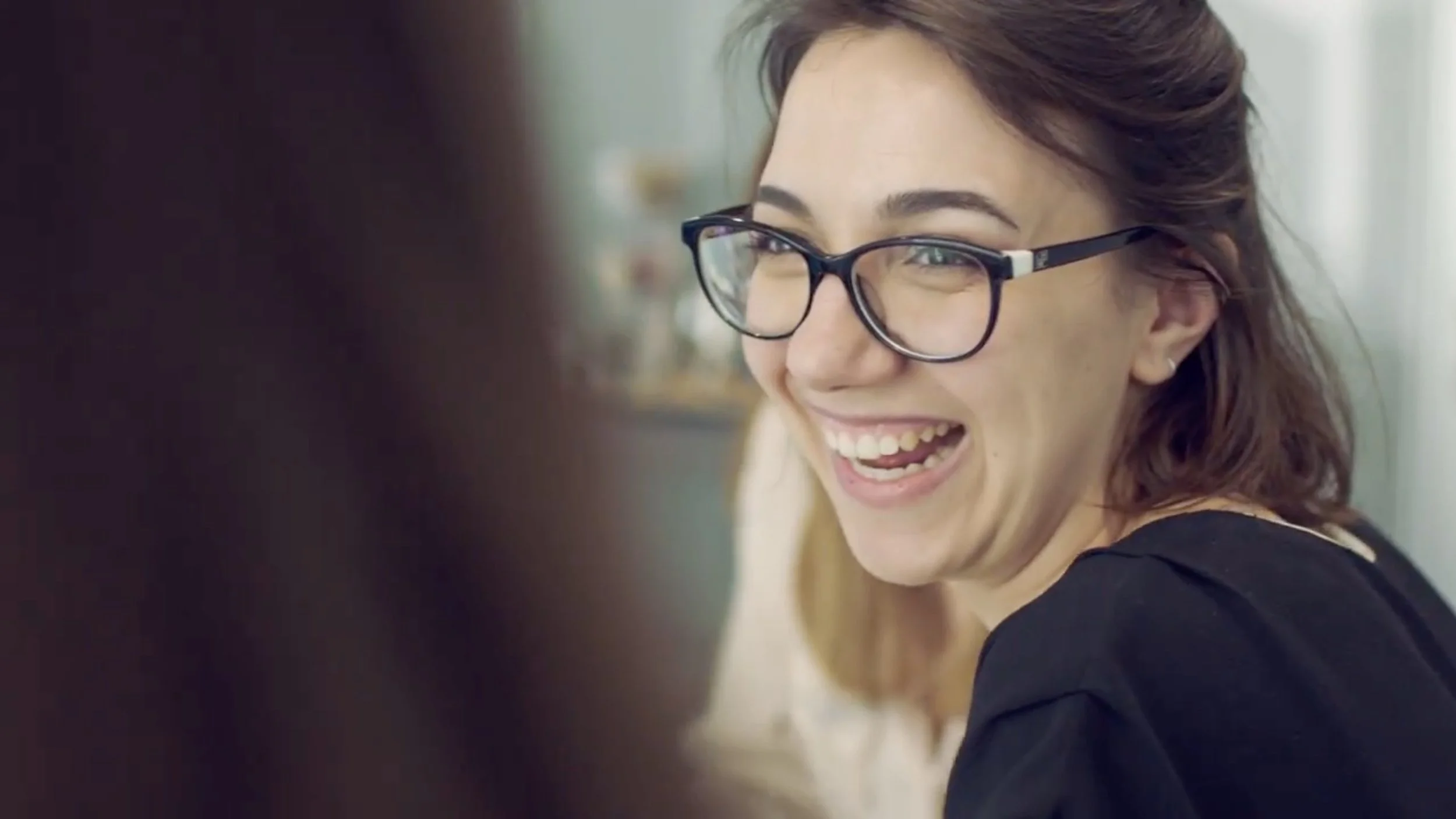 Woman with eyeglasses smiling and laughing.