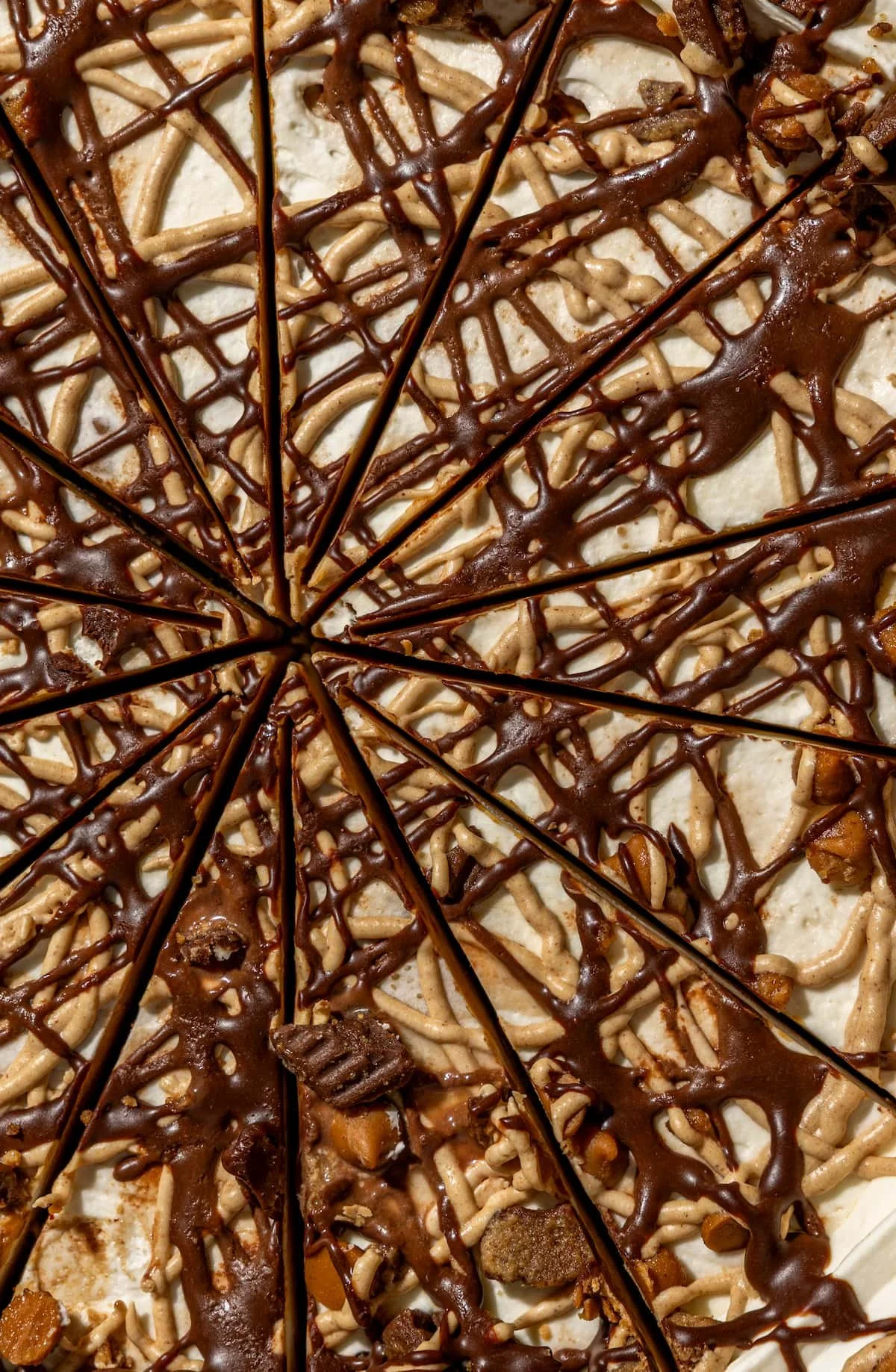 Close-up of a pizza with drizzles of chocolate, topped with caramel and chocolate chunks, sliced into pieces.