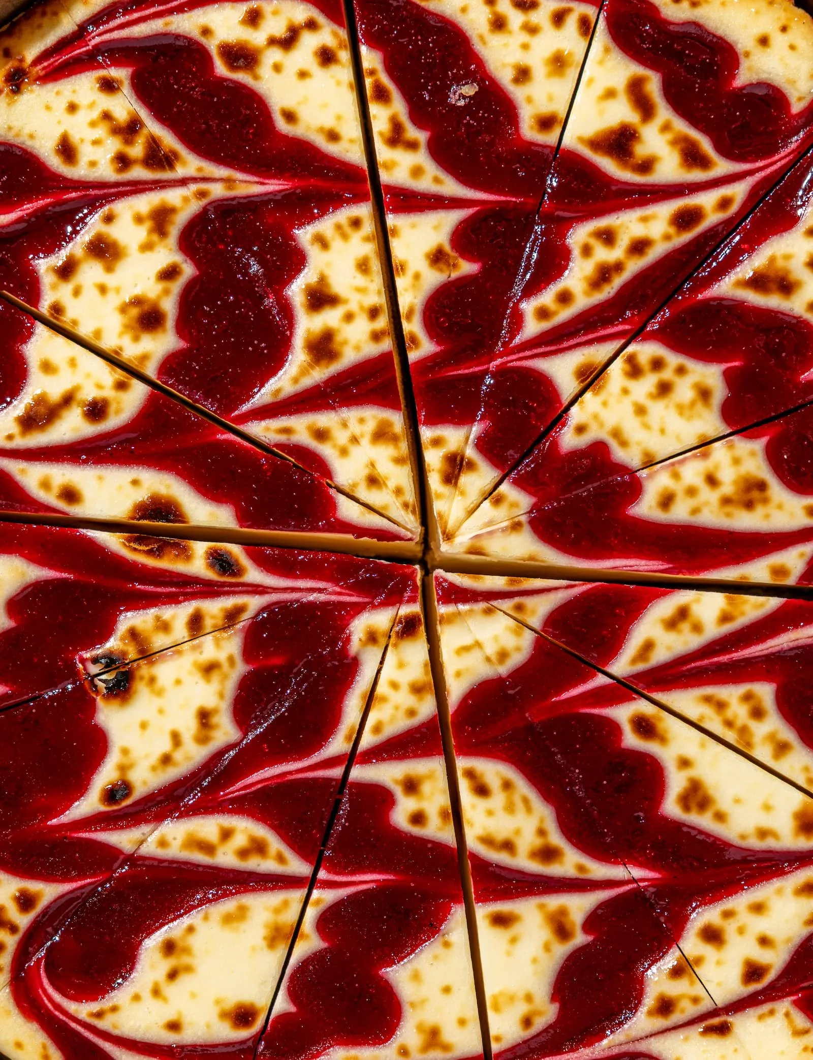 Close-up of a raspberry cheesecake, cut into slices.
