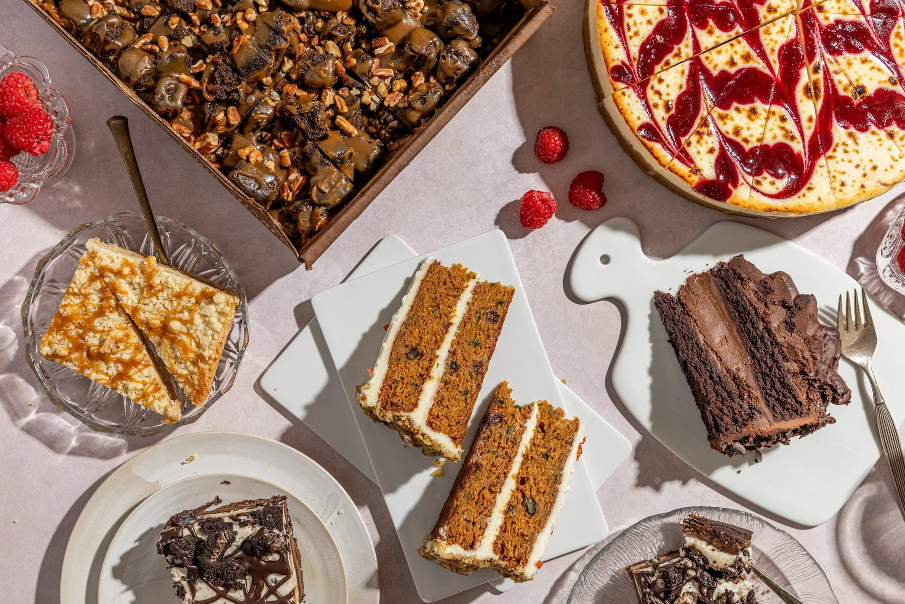 Assorted cakes and desserts on a table, including cheesecake, layered cake, brownie and pie slices.