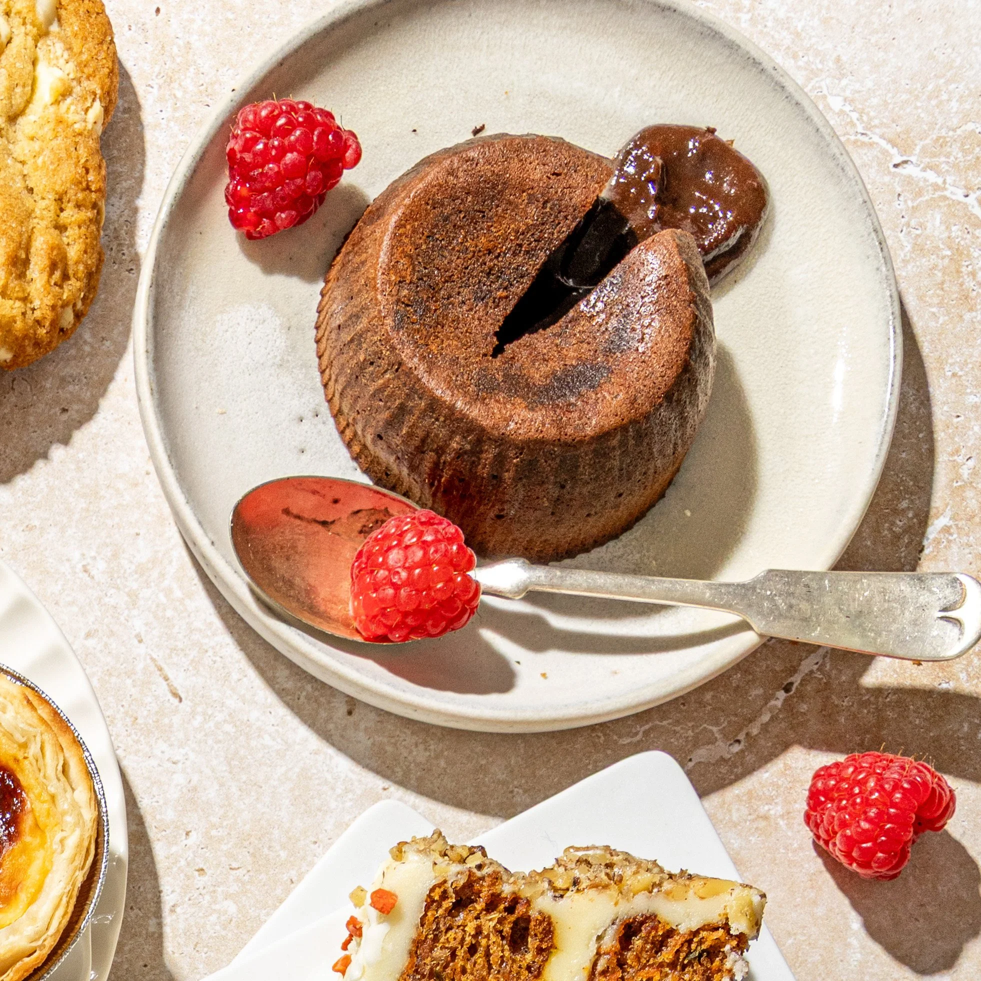 Chocolate lava cake with a fork and fresh raspberries on a plate.