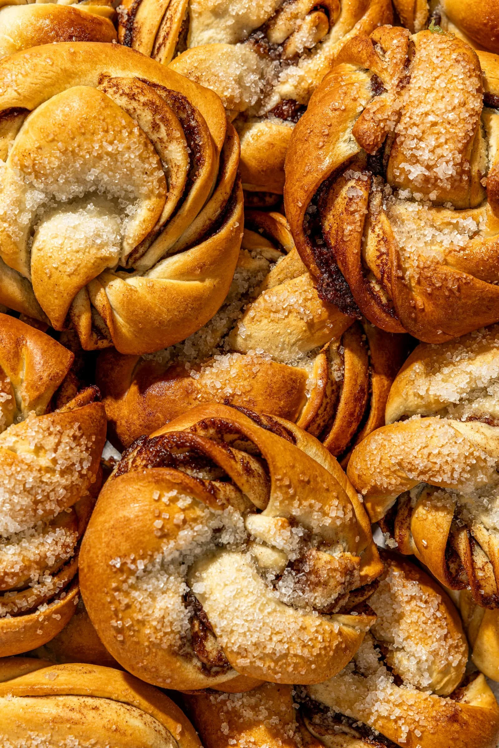 Close-up of freshly baked cinnamon rolls topped with coarse sugar crystals.