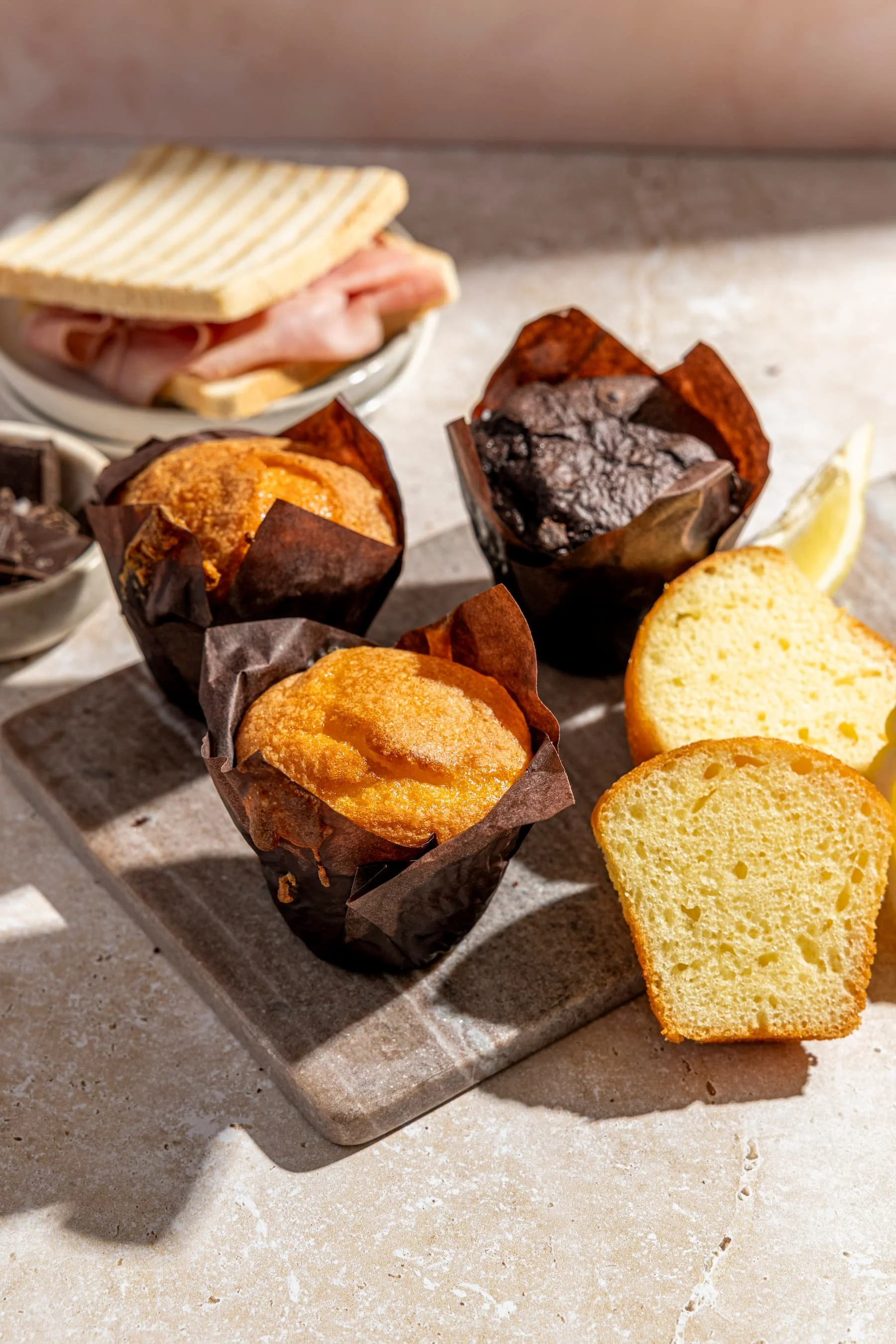 Assorted muffins and a toast in the background arranged on a serving surface.