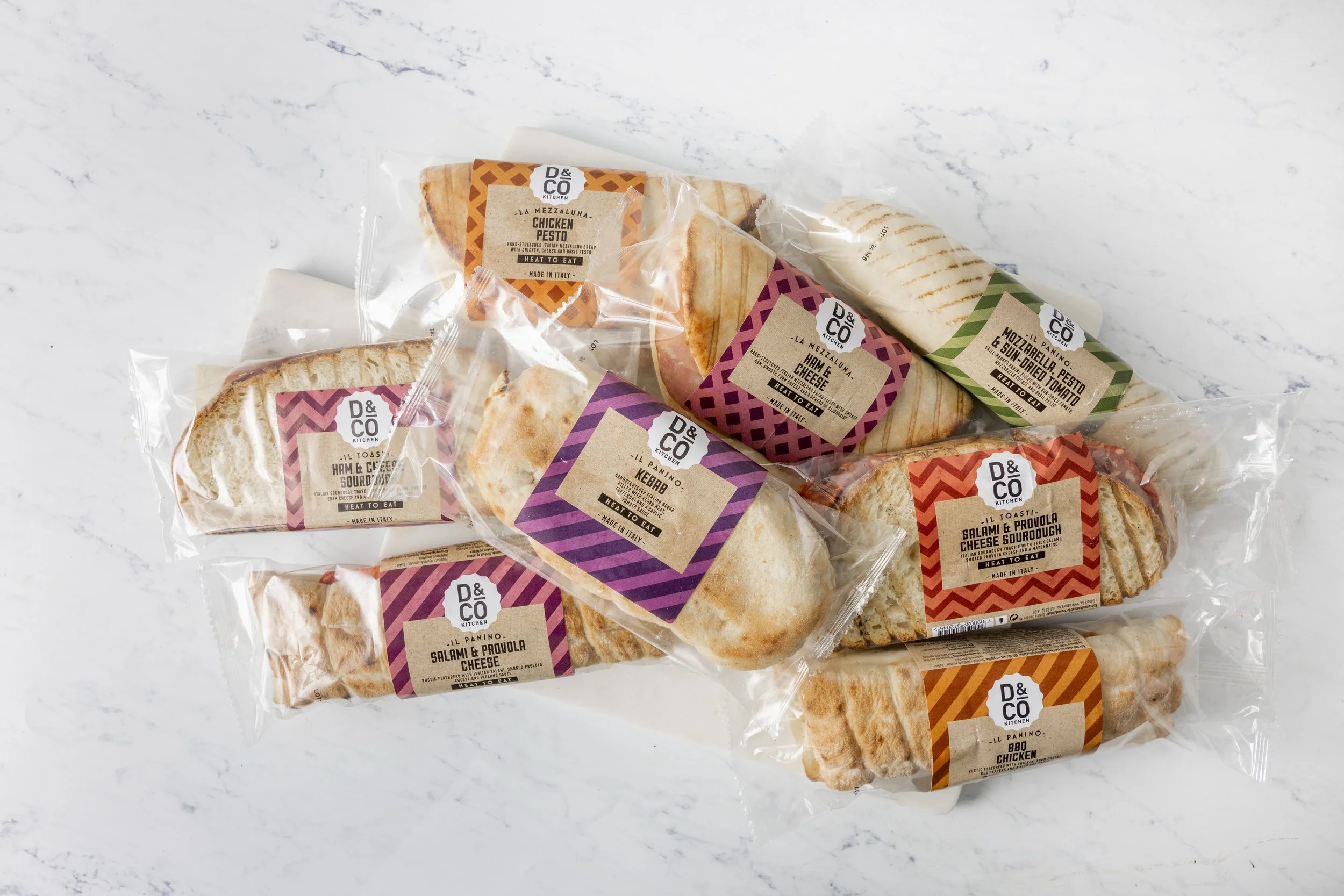 Assorted packaged sandwiches in clear plastic wrappers on a white surface.