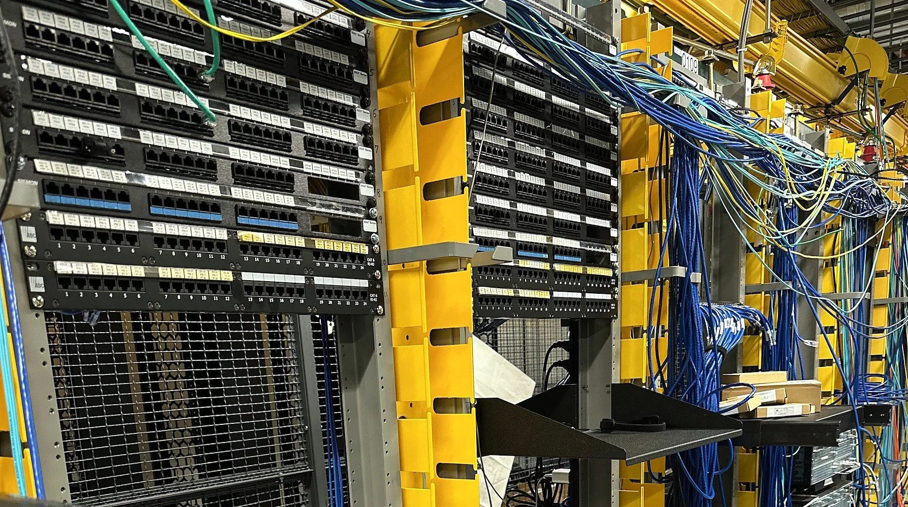 Network racks with patch panels and yellow vertical cable managers