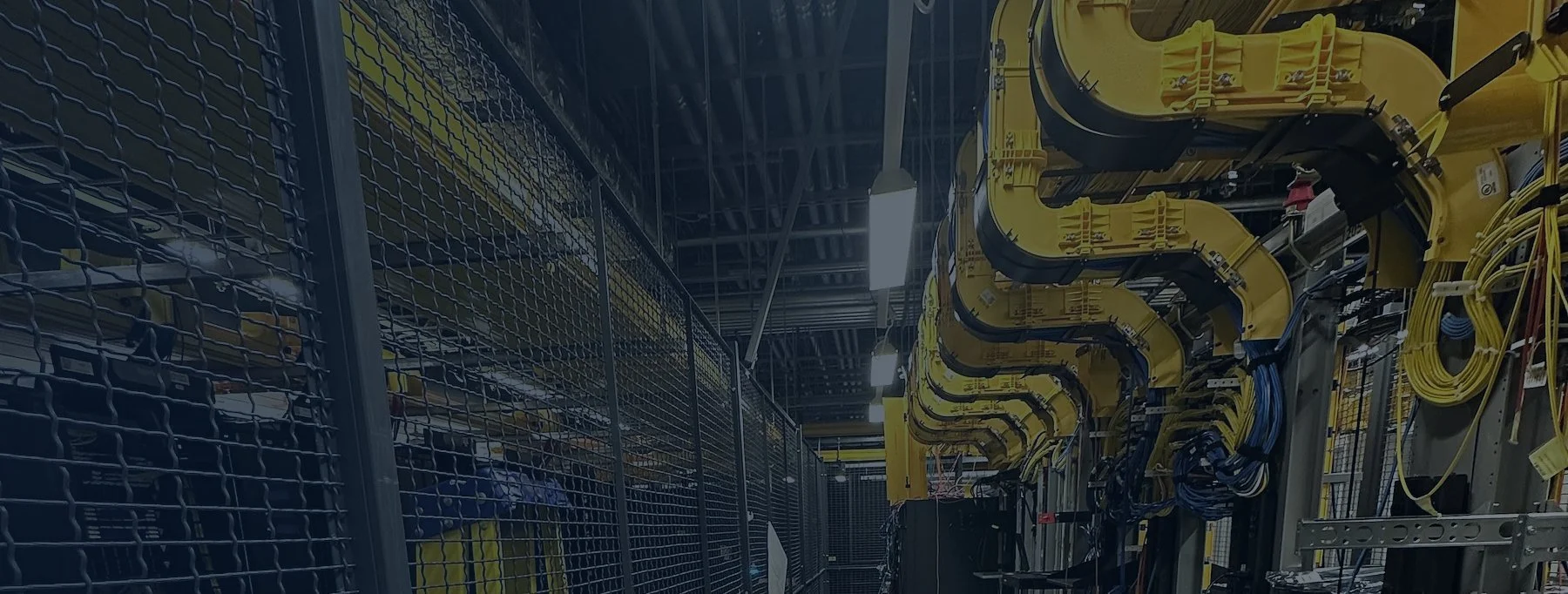 Data center aisle with cages and overhead yellow fiber raceway