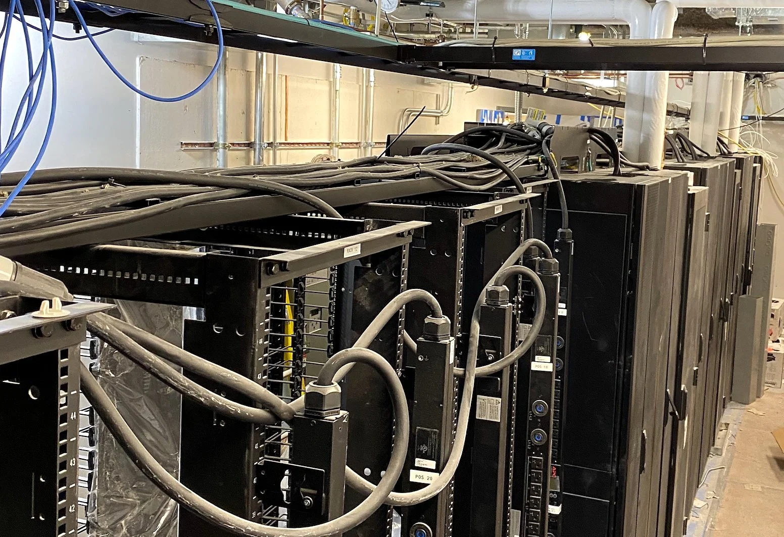 Row of data center cabinets with PDUs and overhead cabling