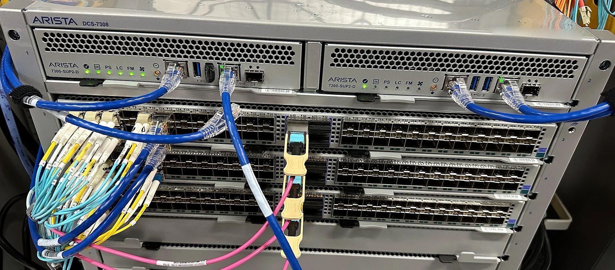 Modular chassis switch with aqua and pink multimode fiber patched to its line cards